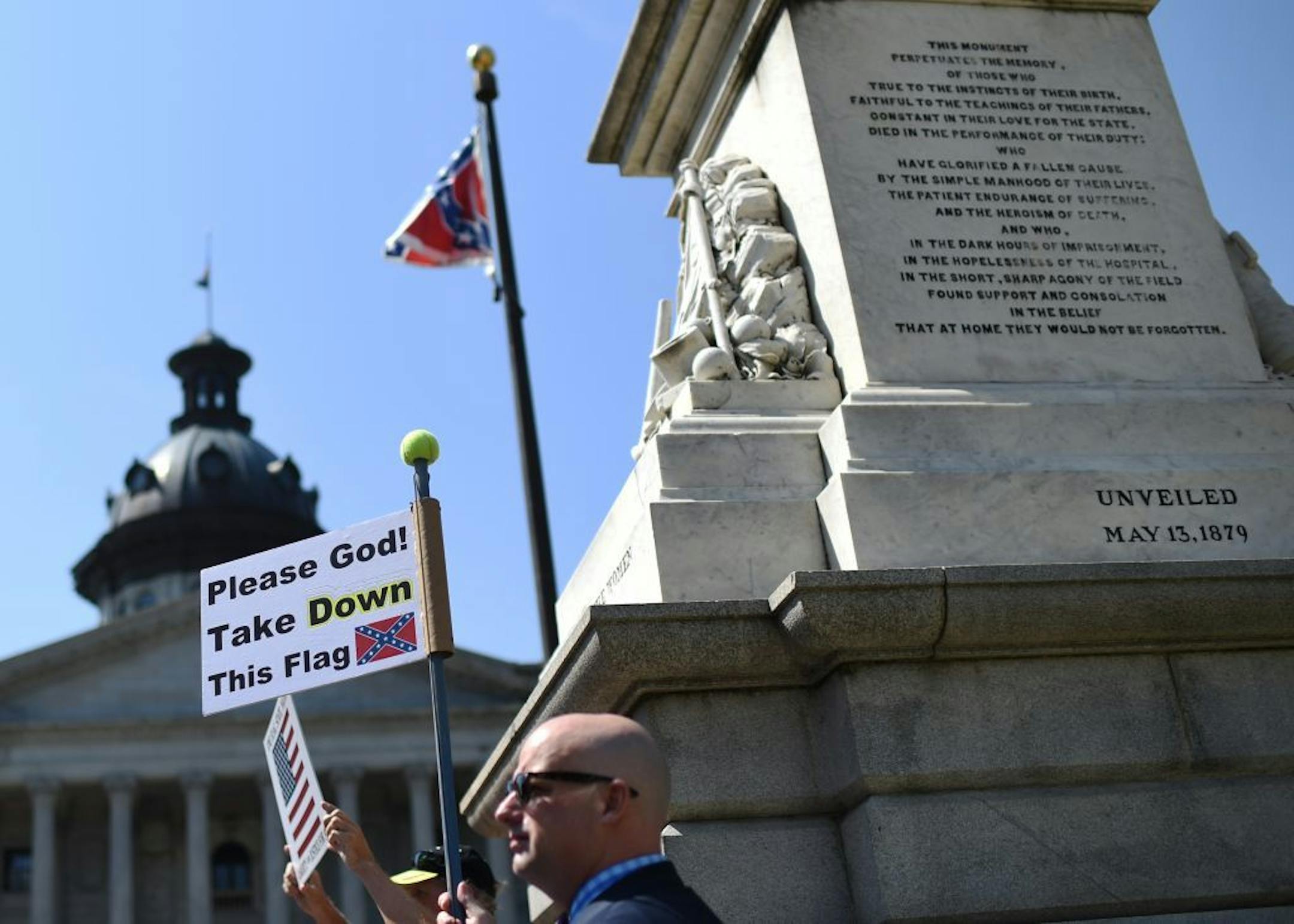 Christian Mergner, of Columbia, S.C., holds a sign during a rally to take down the Confederate flag at the South Carolina Statehouse, Tuesday, June 23, 2015, in Columbia, S.C.