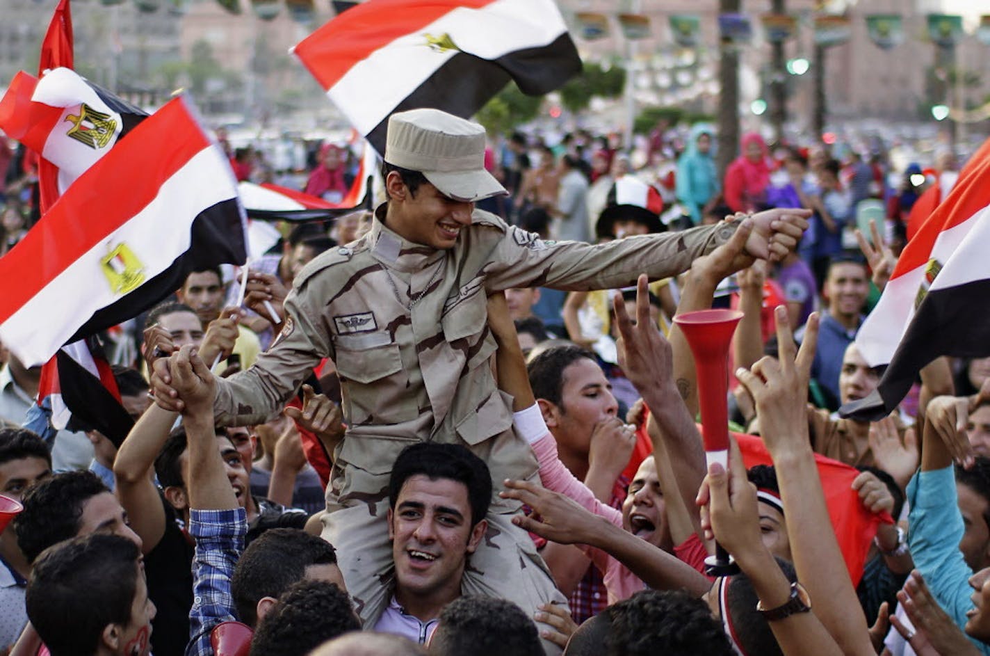 A man carries a member of the Egyptian forces on his shoulders as they join others to celebrate the new Suez Canal opening, while gathering around Tahrir Square in downtown Cairo, Egypt, Thursday, Aug. 6, 2015. With much pomp and fanfare, Egypt on Thursday unveiled a major extension of the Suez Canal billed by its patron, President Abdel-Fattah el-Sissi as a historic achievement needed to boost the country's ailing economy after years of unrest. (Ahmed Abd El-Latif/El Shorouk newspaper via AP)