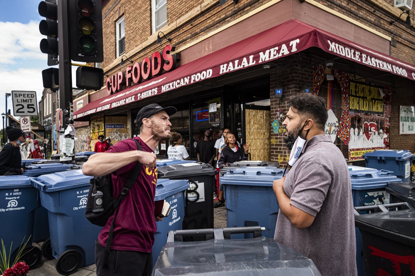 Cup Foods worker Billy Abumayyaleh, right, brother to owner Mahmoud Abumayyaleh, was confronted by an activist on Monday, Aug. 3. He was trying to clear the garbage cans placed in front of his store by activists to block shoppers from entering.