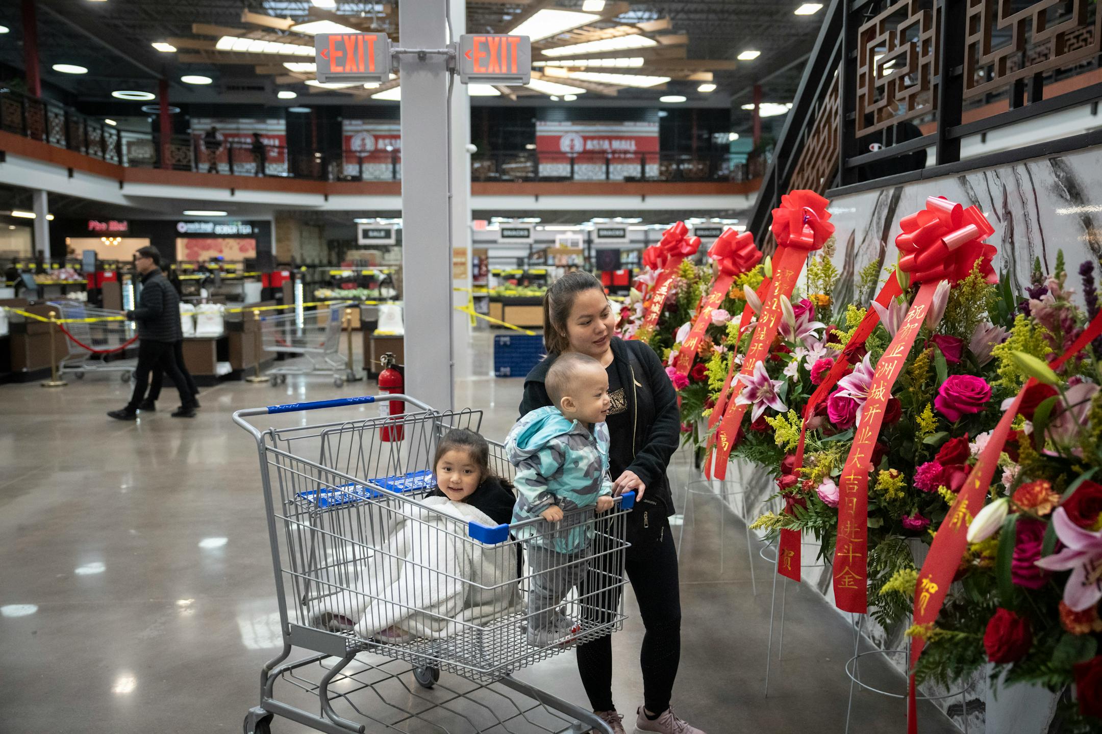 Truc Pham walks her children Abigail Nguyen, 5, and Lucas Nguyen, 1, up to the fresh flower display at a soft opening for the new Asia Mall. Pham was excited for the new mall because she used to go to a similar one in California to find traditional food from Vietnam.