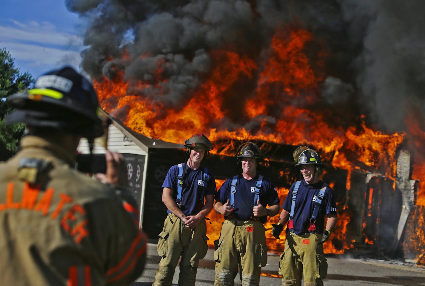 All IN THE FAMILY: Three generations of firefighters posed for a photo after a Stillwater Fire Department training burn, including, from right, Tim Bell, 65; Jon Bell, 45; and Jake Bell, 27. At top, Brad Junker rolled up hose after the exercise.