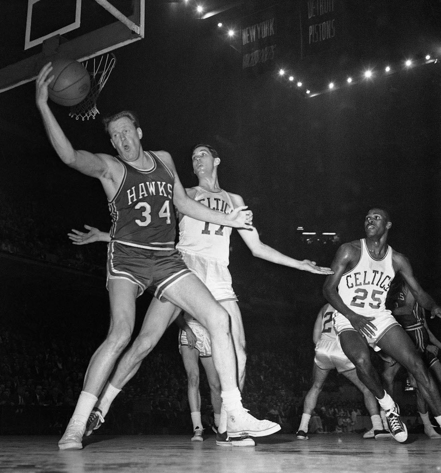 FILE - In this Jan. 13, 1960, file photo, Clyde Lovellette (34), then with the St. Louis Hawks, snags a ball from going out of bounds as Boston Celtics' Gene Conley defends during an NBA basketball game in Boston.