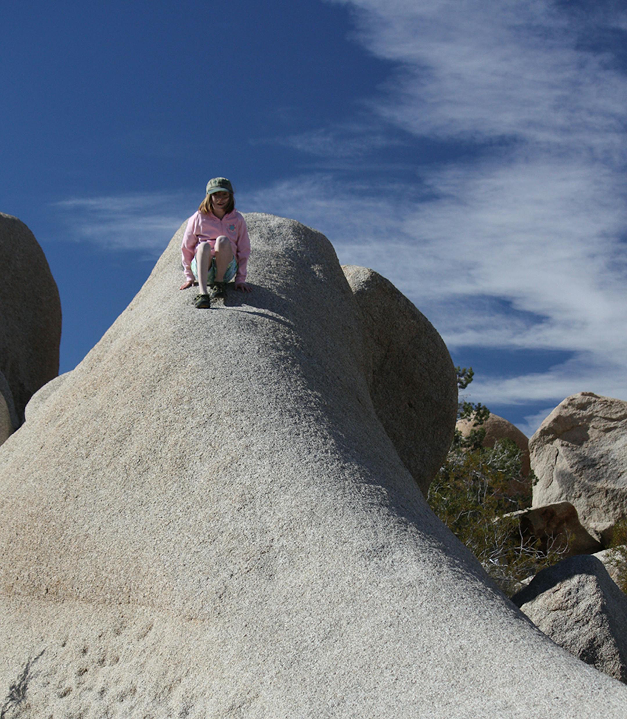 Jane Lundquist climbs a rock in the vast desert landscape of Joshua Tree National Park.