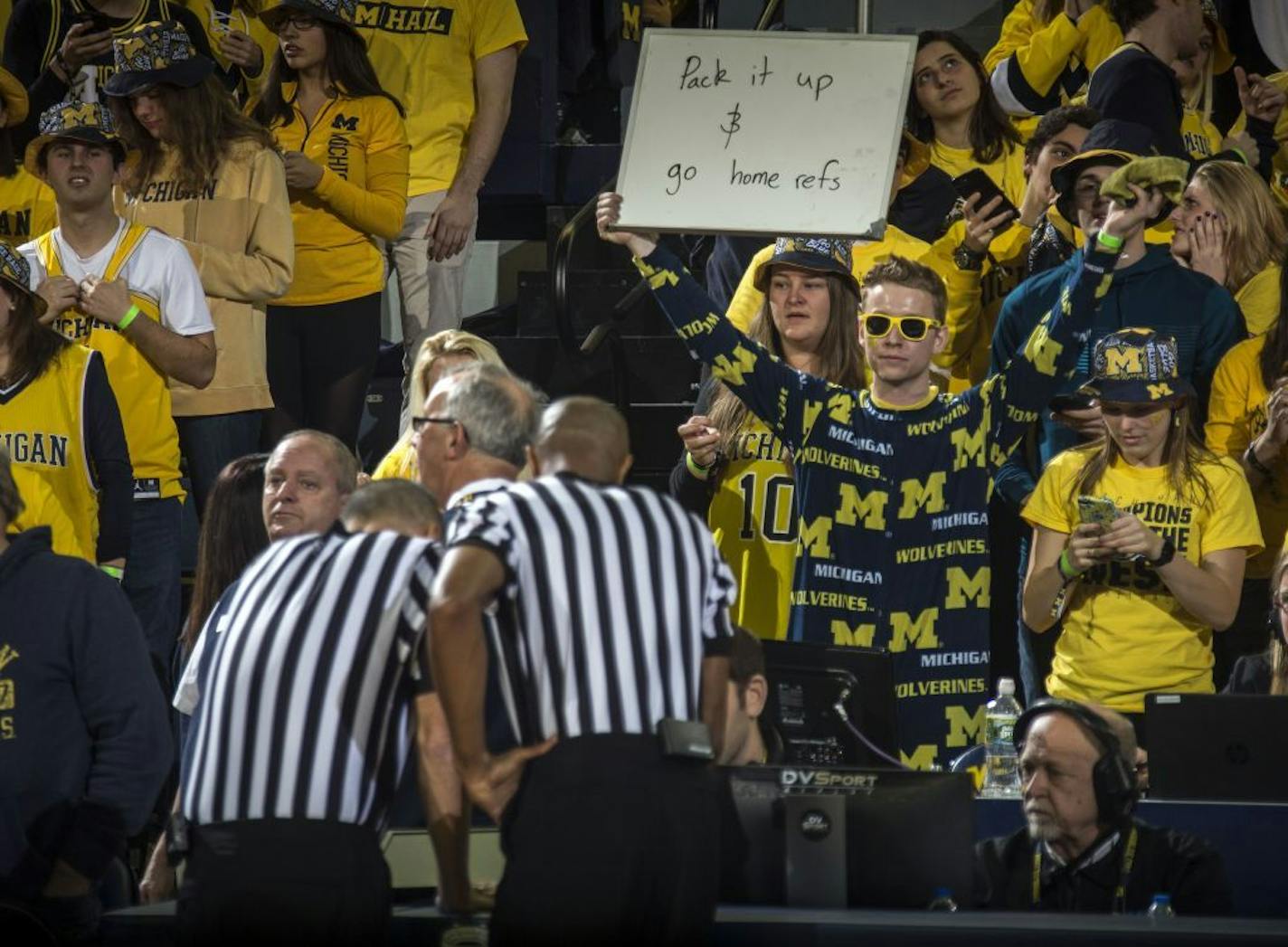 A Michigan fan in the student section holds up a sign at referees at the game official review a buzzer-beater at the end of an NCAA college basketball game between Michigan and Minnesota, at Crisler Center in Ann Arbor, Mich., Tuesday, Jan. 22, 2019. Michigan won 59-57.