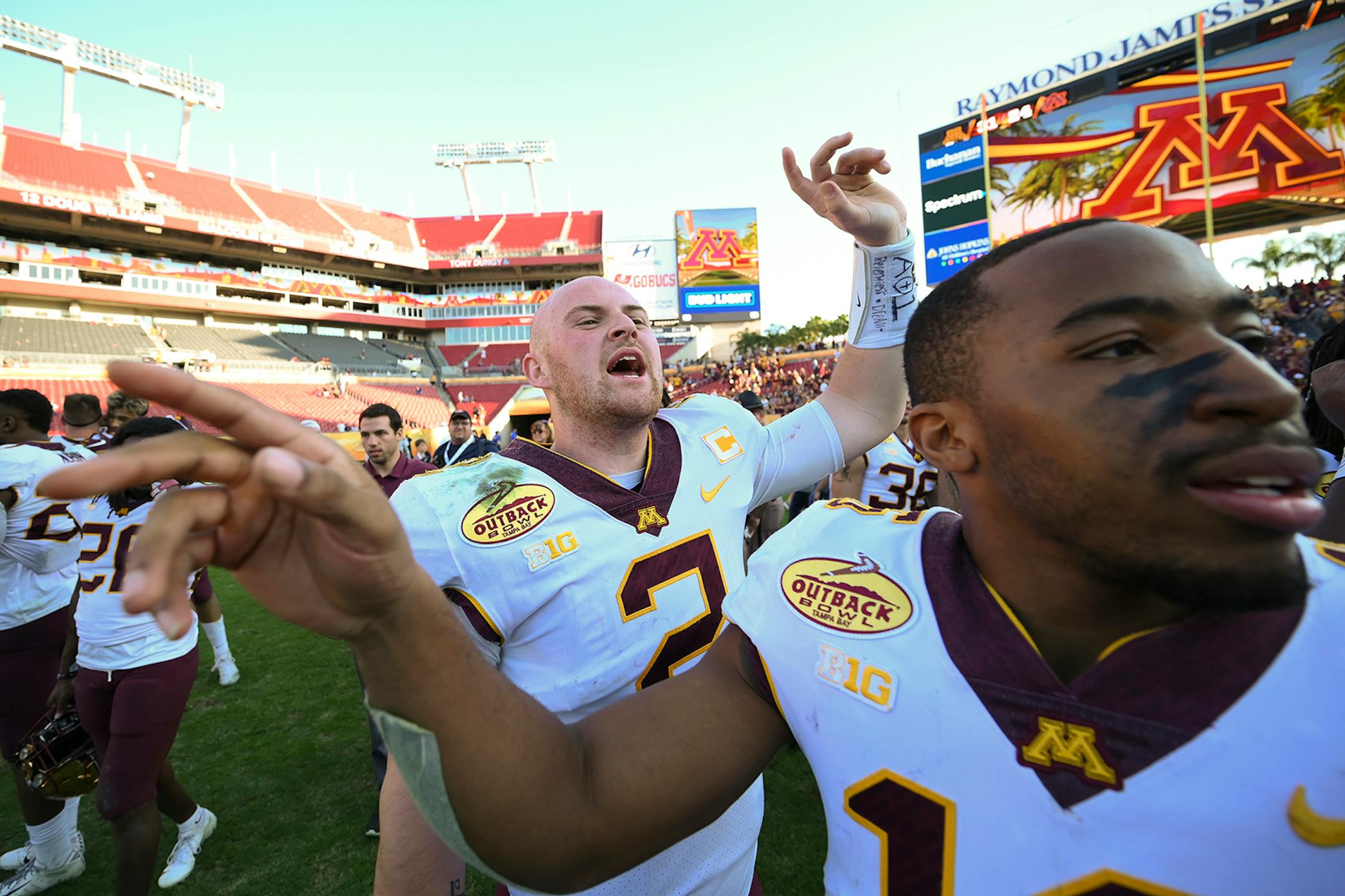 Minnesota Gophers quarterback Tanner Morgan (2) and defensive back Coney Durr (16) wrangled teammates for a team photo after their win against the Auburn Tigers.