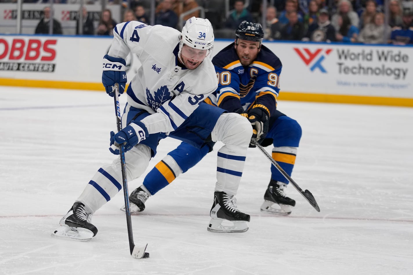 Toronto Maple Leafs' Auston Matthews (34) brings the puck down the ice as St. Louis Blues' Ryan O'Reilly (90) defends during during the third period of an NHL hockey game Tuesday, Dec. 27, 2022, in St. Louis. (AP Photo/Jeff Roberson)