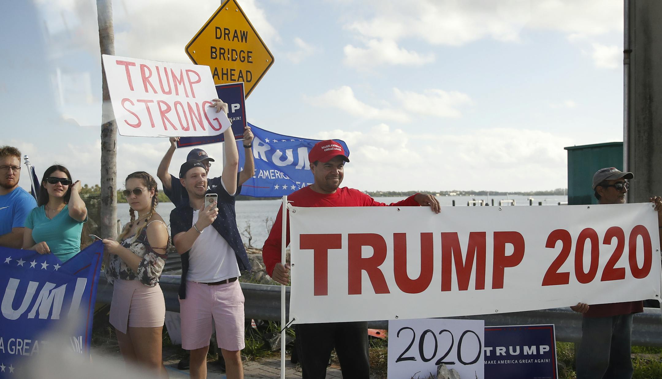 A group of President Donald Trump supporters is seen from the media van traveling in the president's motorcade en route to his Mar-a-Lago estate in Palm Beach, Fla., Tuesday, Dec. 26, 2017. (AP Photo/Carolyn Kaster)