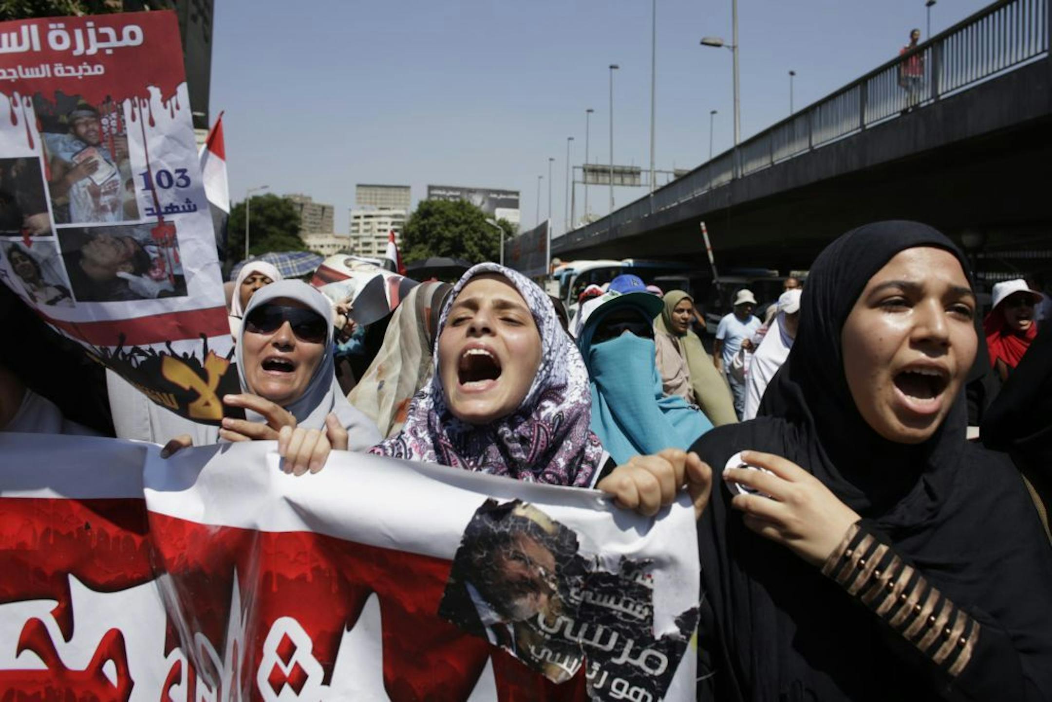 Supporters of Egypt's ousted President Mohammed Morsi chant slogans as they march on a street in Cairo, Egypt, Monday, July 22, 2013. The family of ousted Egyptian President Mohammed Morsi accused the country's military generals Monday of "kidnapping" him, and said that it holds the army responsible for his "safety and security." Partial translation of they poster at left in Arabic reads, "El-Sissi massacre," and "Morsi is my president," at center.
