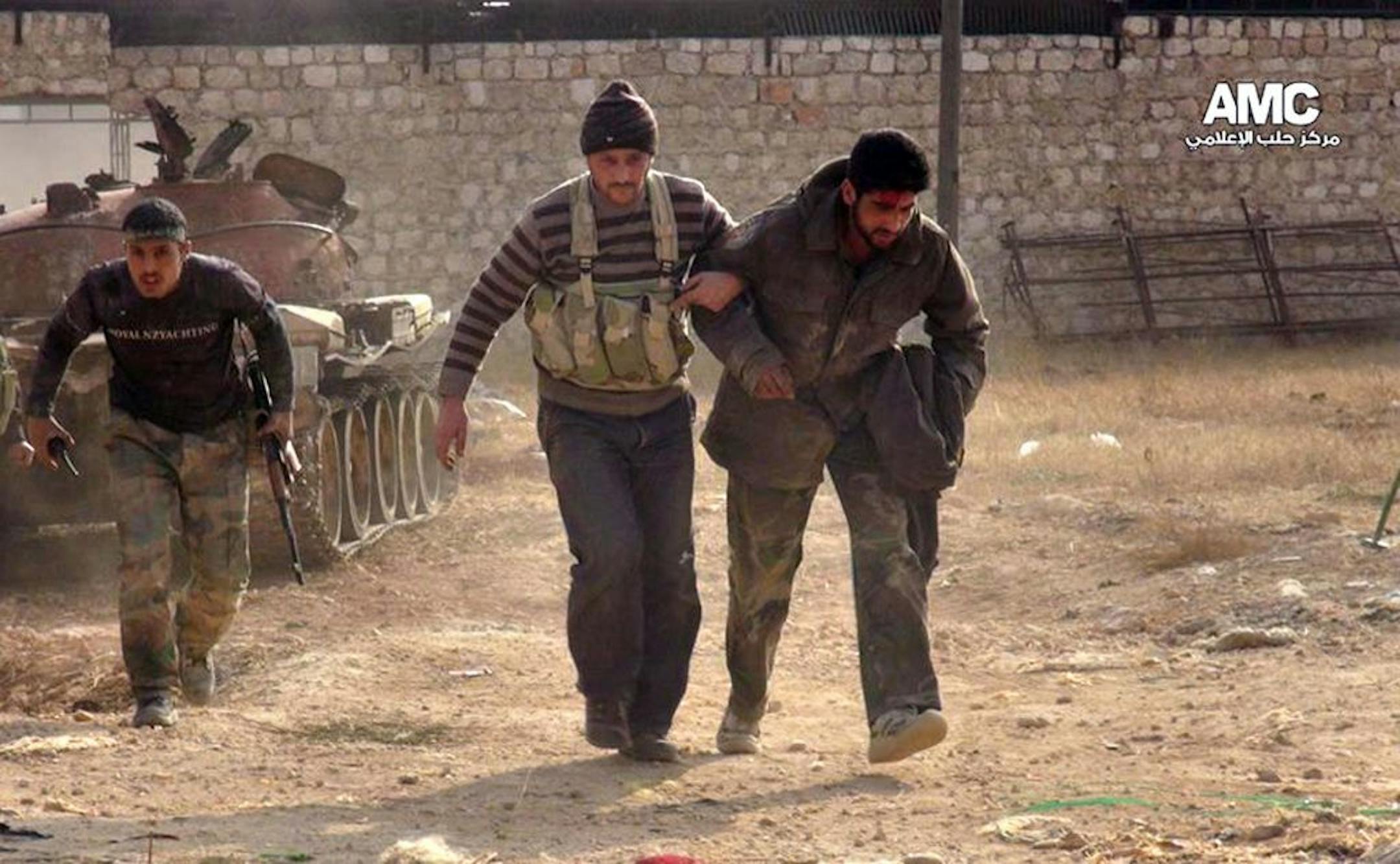 This Monday, Nov. 11, 2013 citizen journalism image provided by Aleppo Media Center AMC shows two Free Syrian Army fighters helping a wounded comrade during clashes in Aleppo, Syria.