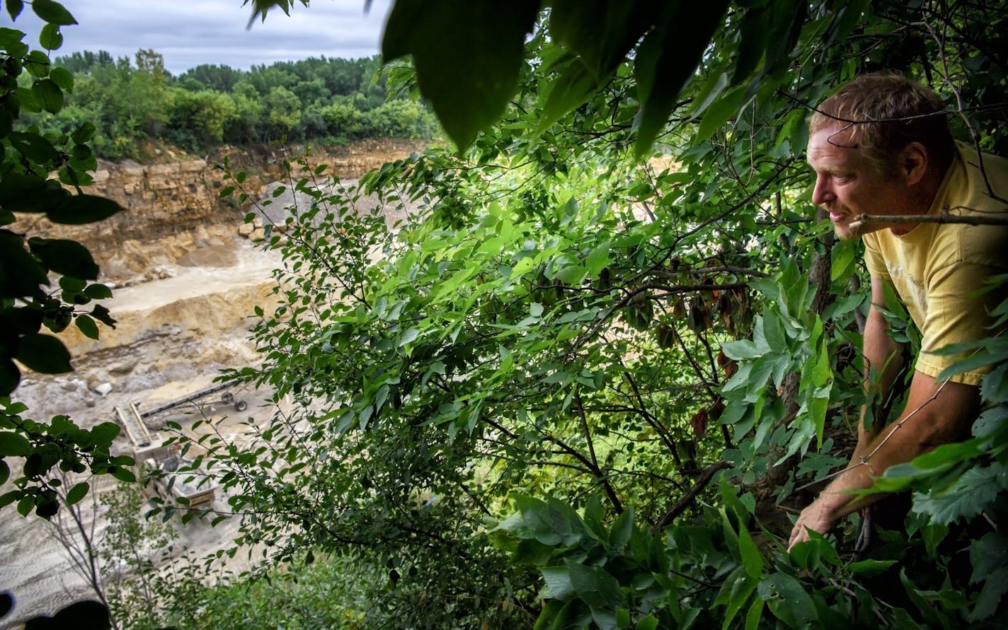 Mike Sprenger walked through the small bank of trees that separates the quarry from neighbors&#x2019; homes. He said he saw quarry workers quickly gathering rocks after the blast and throwing them into these woods.