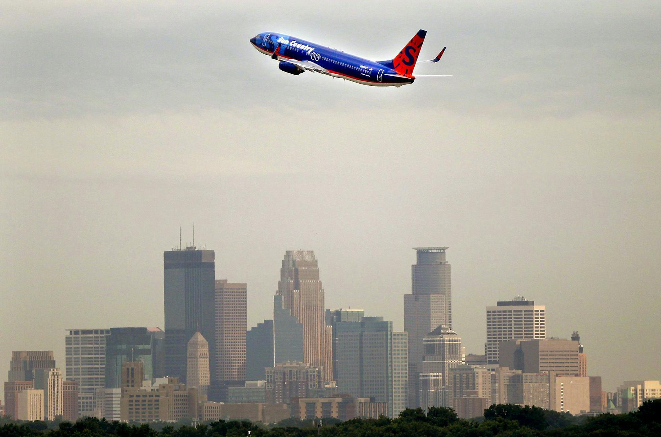 A Sun Country airplane made its way over the Minneapolis skyline early Friday, July 22, 2011, after taking off from the Humphrey terminal in Bloomington, MN.] (ELIZABETH FLORES/STAR TRIBUNE) ORG XMIT: MIN2012091818201199