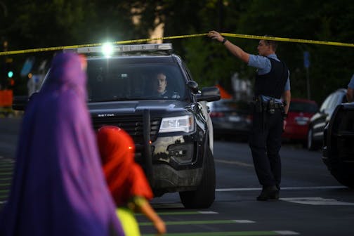 A family crossed Chicago Avenue as a Minneapolis Police officer lifted tape at a crime scene on July 23. Minneapolis residents are still torn over whether the police department is best suited to improve safety in the city months after the police killing of George Floyd.