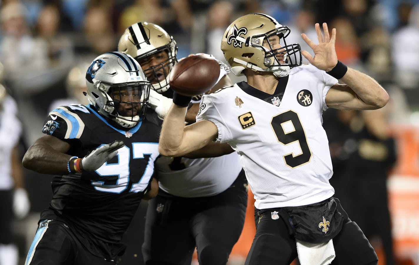 New Orleans Saints' Drew Brees (9) looks to pass under pressure from Carolina Panthers' Mario Addison (97) in the second half of an NFL football game in Charlotte, N.C., Monday, Dec. 17, 2018. (AP Photo/Mike McCarn)