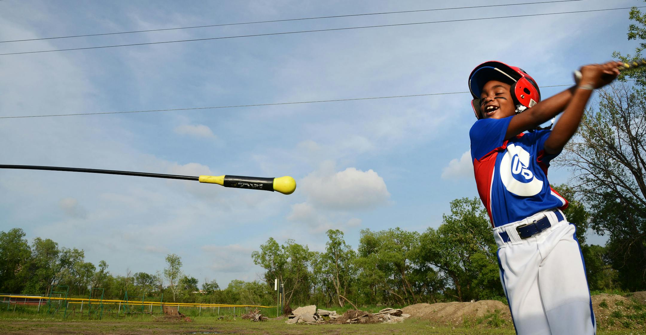 Anija Sheffield, 8, practiced her swing during warm-ups last month at the Little League complex in Brooklyn Center. In the background was debris that had been dumped by unknown parties. The debris has since been removed, with two local companies pitching in.