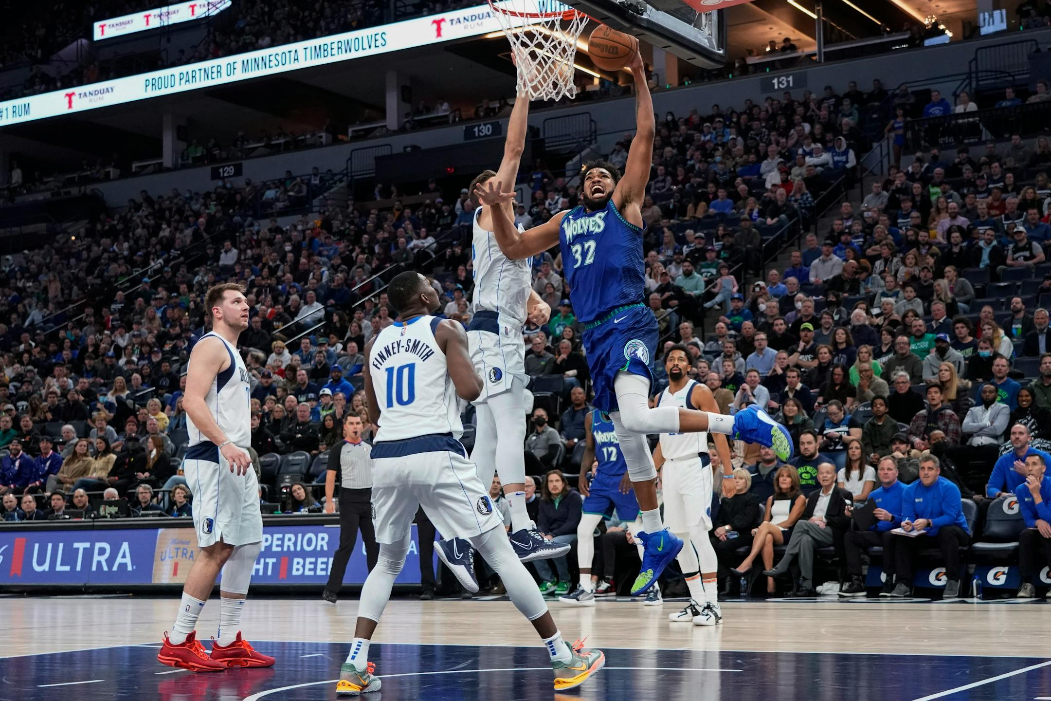 Minnesota Timberwolves center Karl-Anthony Towns (32) goes up for a dunk as Dallas Mavericks forward Maxi Kleber defends and forward Dorian Finney-Smith (10) watches during the first half of an NBA basketball game Friday, March 25, 2022, in Minneapolis. (AP Photo/Craig Lassig)