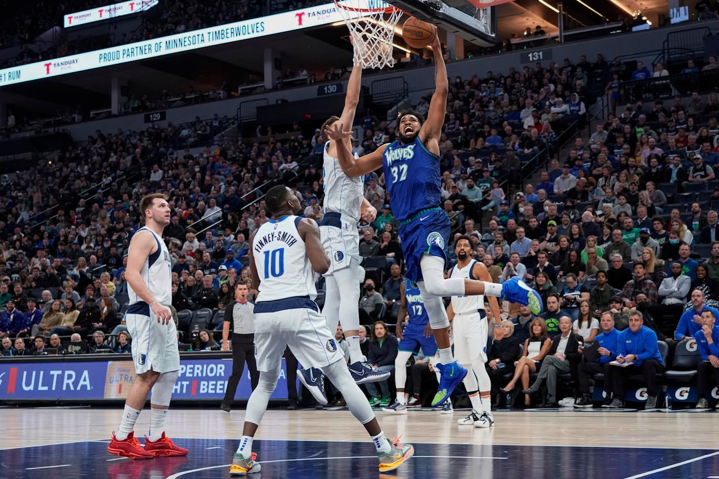 Minnesota Timberwolves center Karl-Anthony Towns (32) goes up for a dunk as Dallas Mavericks forward Maxi Kleber defends and forward Dorian Finney-Smith (10) watches during the first half of an NBA basketball game Friday, March 25, 2022, in Minneapolis. (AP Photo/Craig Lassig)