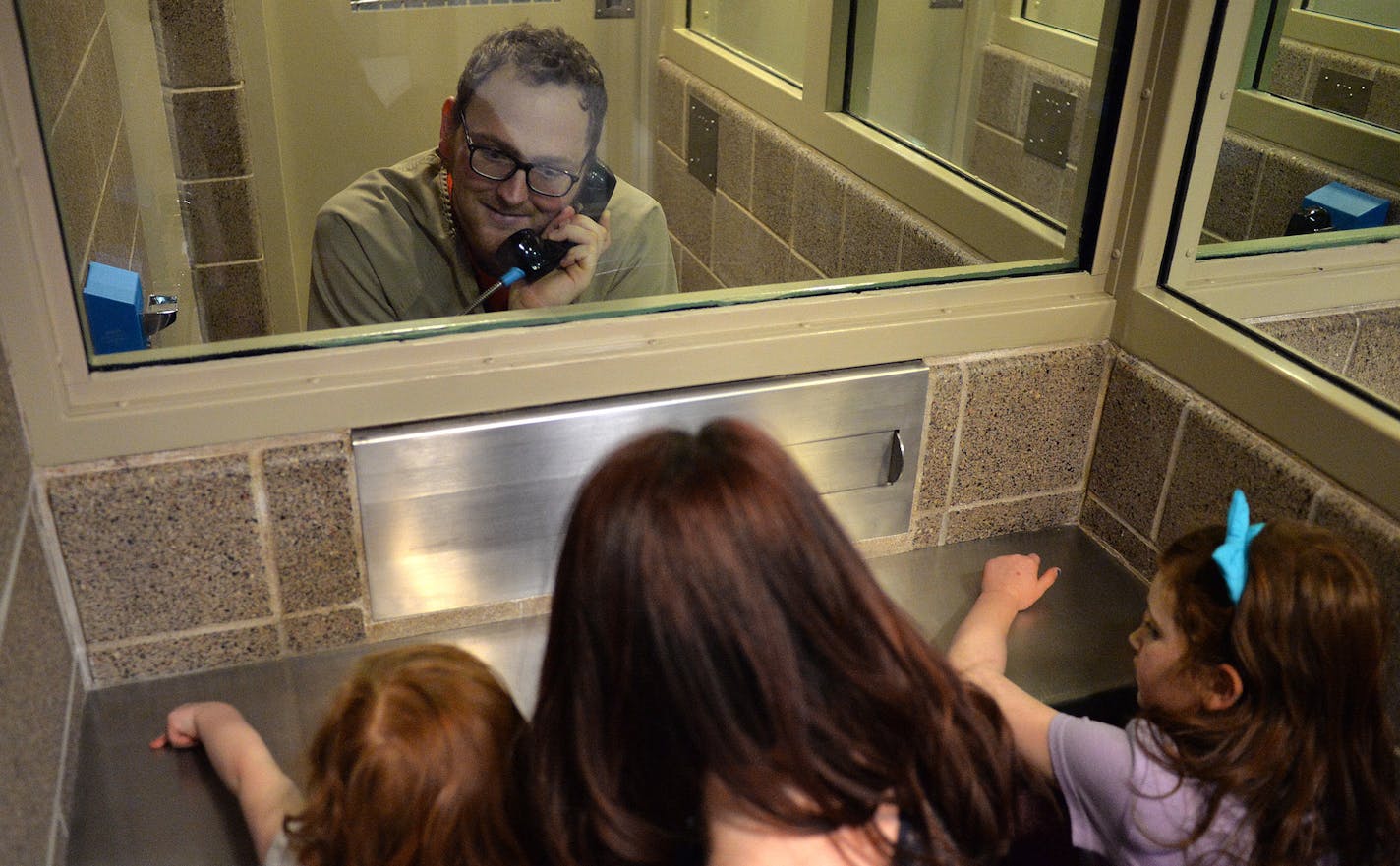 On a recent visit to Washington County jail, Brittany, 30, sits with her children, Kieran, Maia and Lainey, while her husband, and father to her children, Josh, 31, sits on the other side of the security glass. ] (SPECIAL TO THE STAR TRIBUNE/BRE McGEE) **Brittany (31, no last name, Minneapolis), Josh (31, no last name, inmate), Kieran (5, no last name, red sleeves), Maia (7, no last name, blue bow in hair), Lainey (3, no last name, white t-shirt)