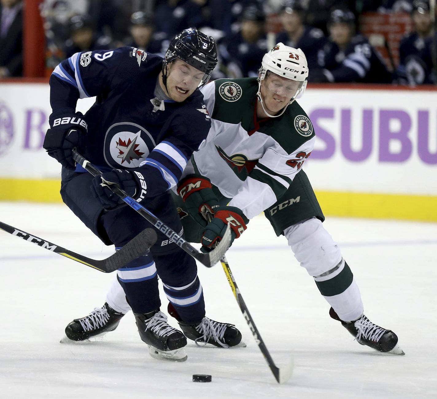 Winnipeg Jets' Andrew Copp (9) and Minnesota Wild's Gustav Olofsson (23) battle for the puck during second period NHL hockey action in Winnipeg, Manitoba, Monday, Nov. 27, 2017. (Trevor Hagan/The Canadian Press via AP)