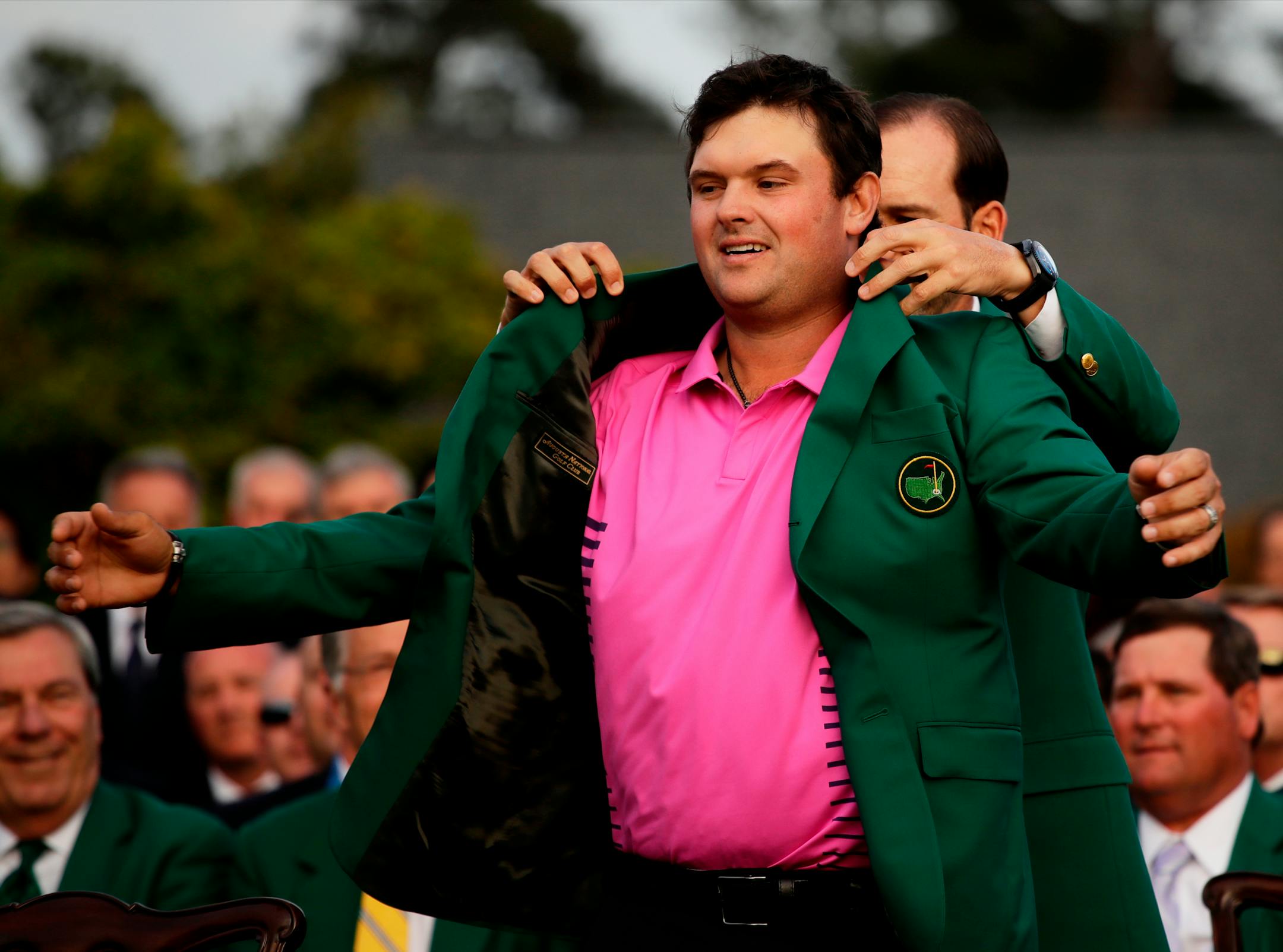 Former Masters champion Sergio Garcia helps Patrick Reed with his green jacket after winning the Masters