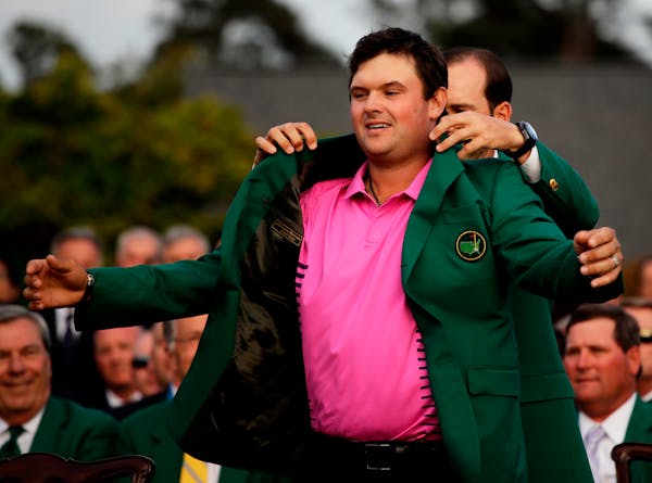 Former Masters champion Sergio Garcia helps Patrick Reed with his green jacket after winning the Masters