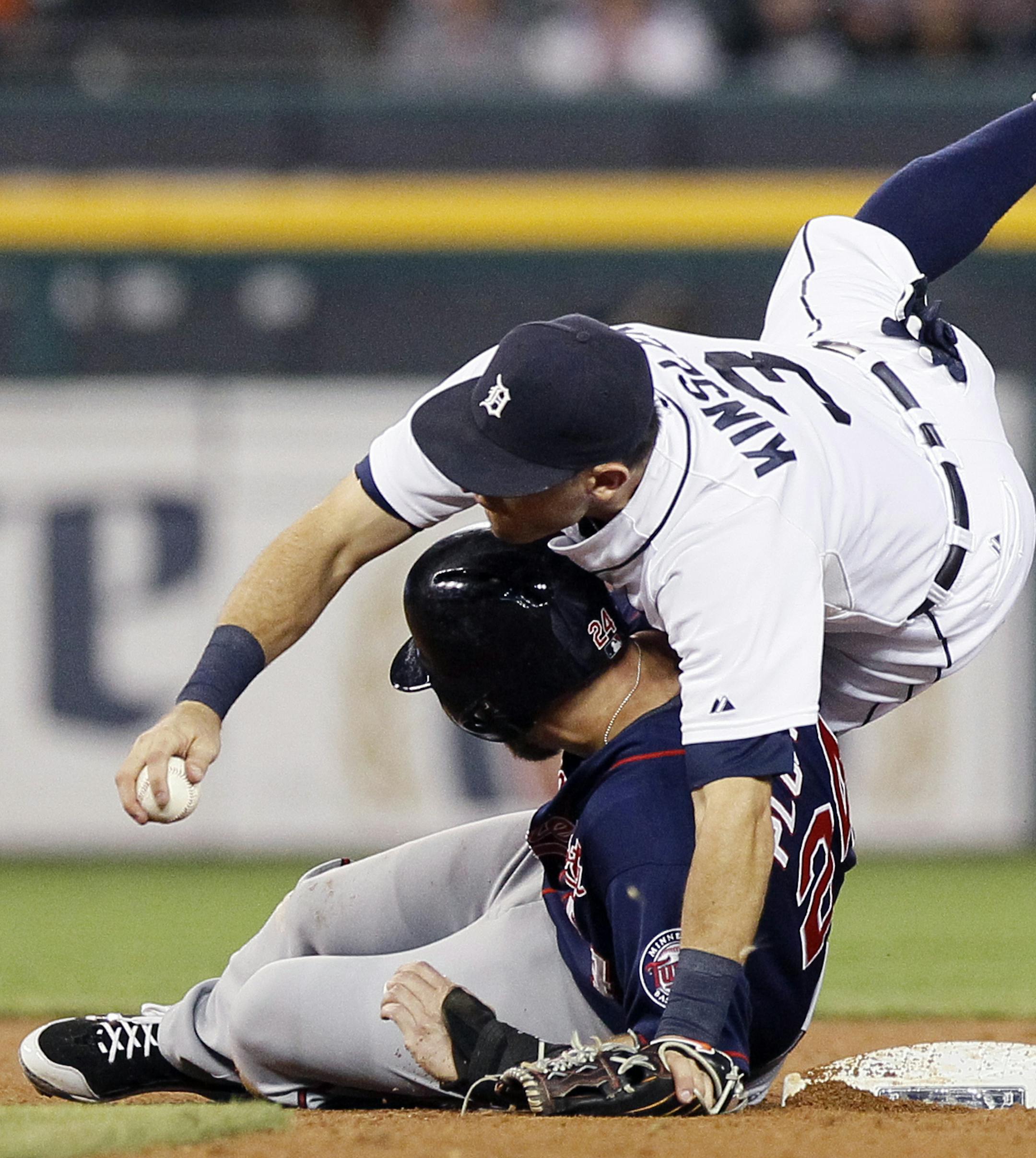 Detroit Tigers second baseman Ian Kinsler, top, lands on Minnesota Twins’ Trevor Plouffe after making a leaping catch of a ball thrown by Nick Castellanos during the fifth inning of a baseball game at Comerica Park, Friday, Sept. 25, 2015, in Detroit. Castellanos had fielded a ground ball by Twins' Torii Hunter and then threw it high above Kinsler. All runners were safe. (AP Photo/Duane Burleson)