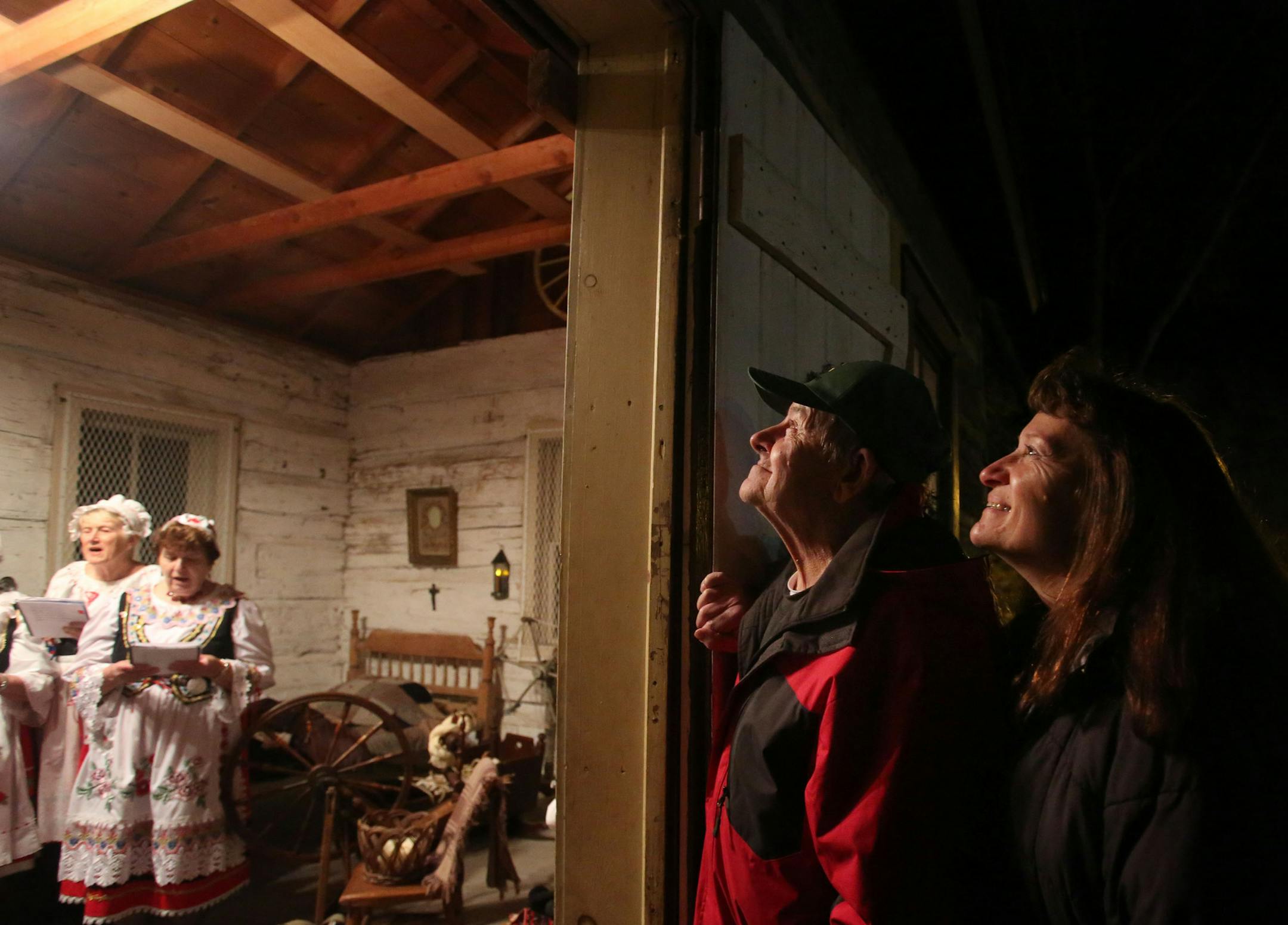 To get in the Holiday spirit, the New Prague Czech singers and several members of the New Prague High choir sang inside and outside the cabin Friday, Dec. 4, 2015, at Memorial Park in New Prague, MN. Here, while enjoying the sounds of the Czech singers, friends Wayne Mader, middle, and Cindy Novak, right, both of New Prague, admired the construction of the cabin.](DAVID JOLES/STARTRIBUNE)djoles@startribune.com The New Prague historical society has completed a historically-accurate, 19th century