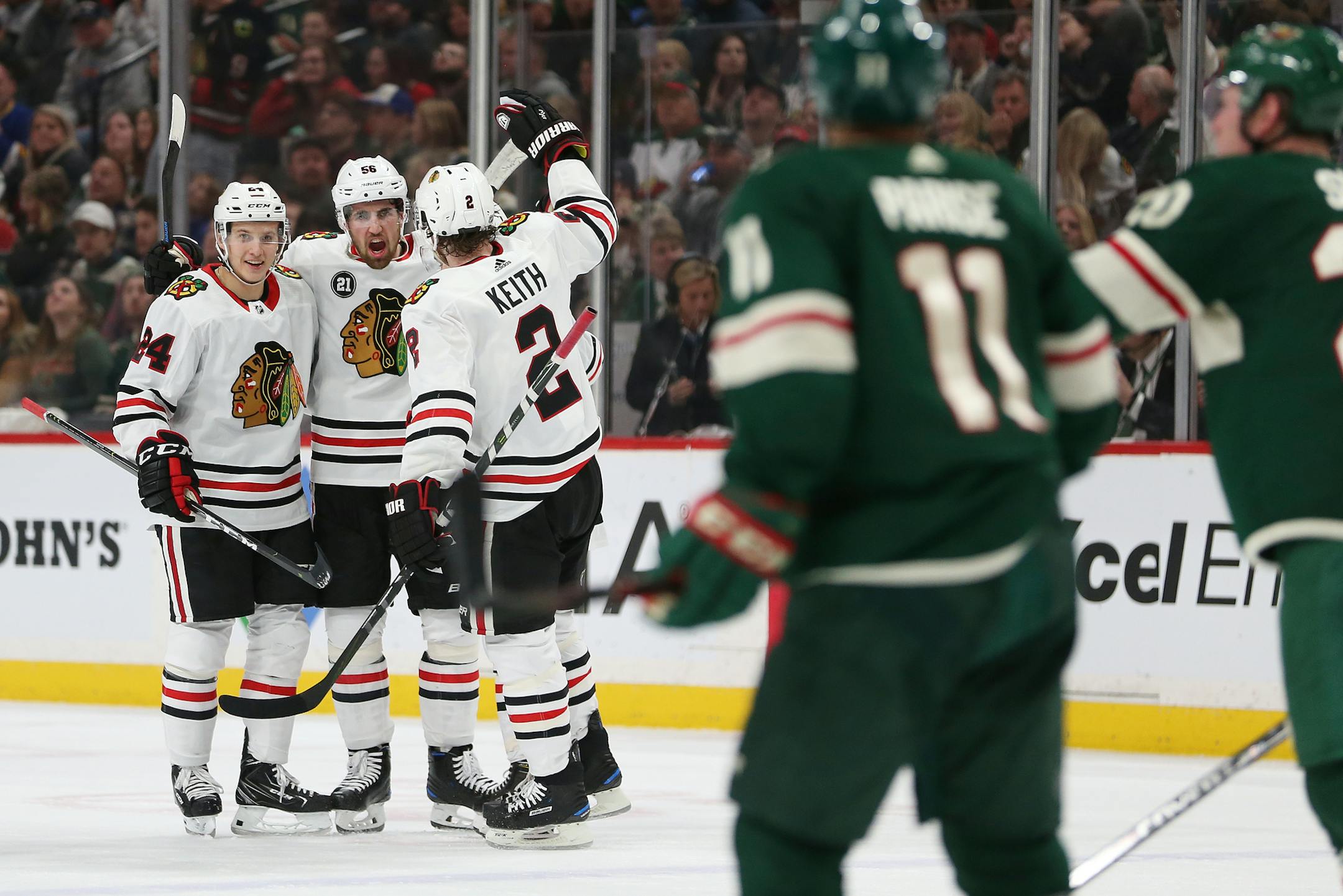 Erik Gustafsson, middle celebrates with teammates Dominik Kahun, left and Duncan Keith after Gustafsson scored a goal against the Wild during the second period. He later won the game in overtime.