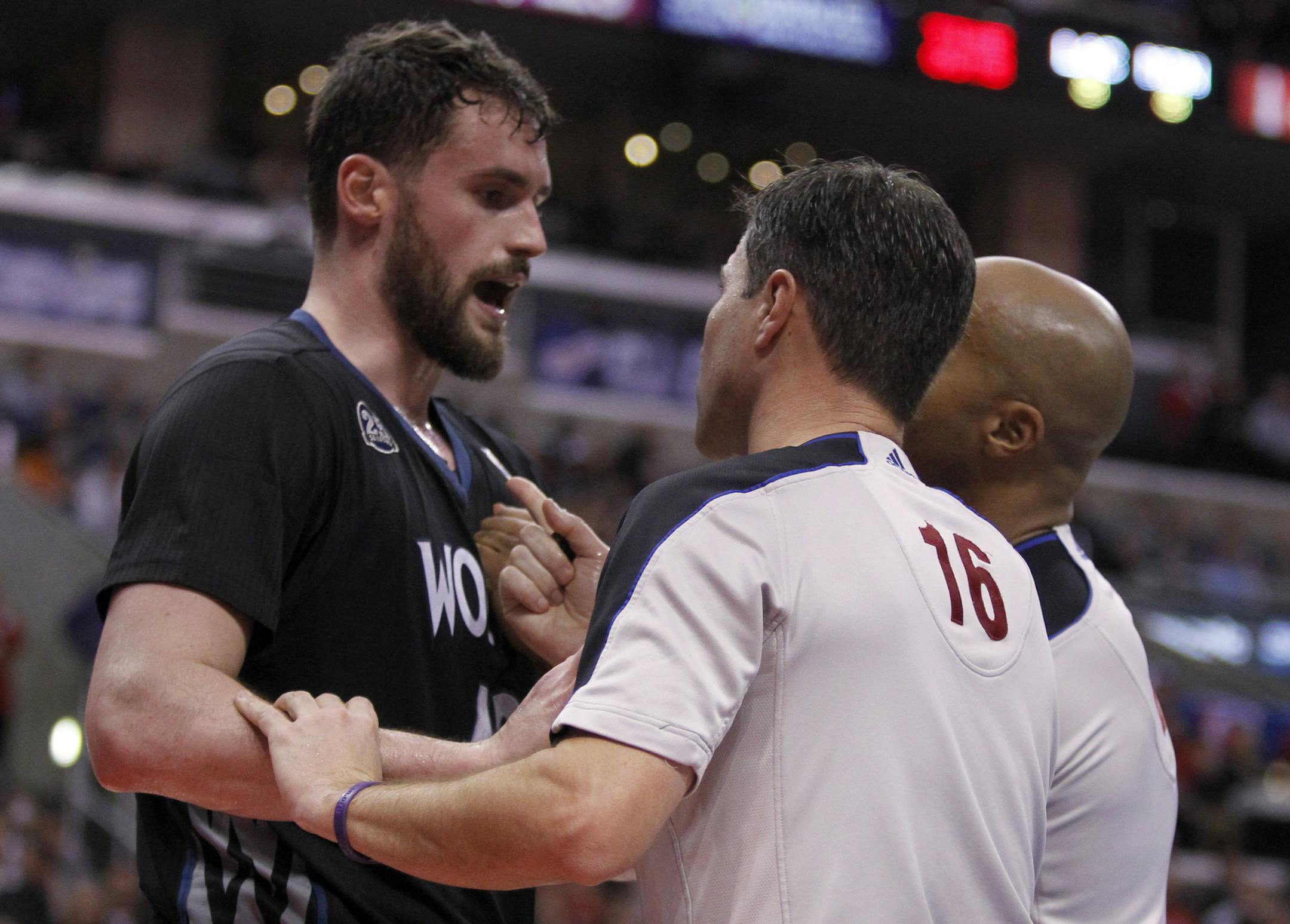 Referees David Guthrie (16) and Marc Davis, right, try to calm down Minnesota Timberwolves forward Kevin Love, left, after a physical foul by Los Angeles Clippers forward Matt Barnes in the second half of an NBA basketball game in Los Angeles on Sunday, Dec. 22, 2013. Clippers forward Matt Barnes was ejected from the game for physical play, but the Clippers won the game 120-116 in overtime. (AP Photo/Alex Gallardo)