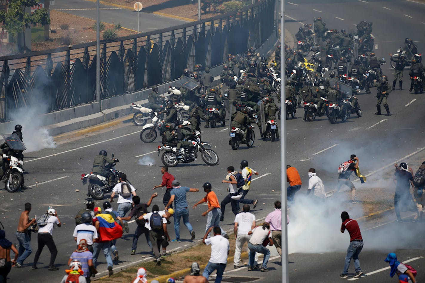 Opponents to Venezuela's President Nicolas Maduro confront loyalist Bolivarian National Guard troops firing tear gas at them outside La Carlota military airbase in Caracas, Venezuela, Tuesday, April 30, 2019. Venezuelan opposition leader Juan Guaidó took to the streets with activist Leopoldo Lopez and a small contingent of heavily armed troops early Tuesday in a bold and risky call for the military to rise up and oust socialist leader Nicolas Maduro.