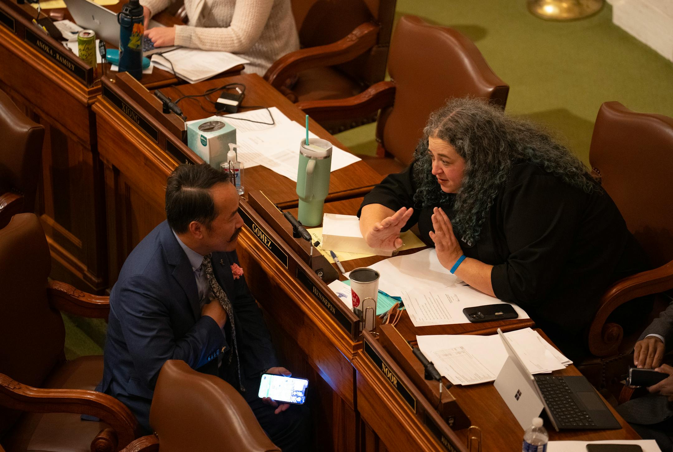 Aisha Gomez, DFL, 62A, Minneapolis conferred with Ethan Cha, DFL, 47B, Woodbury while a discussion took place on the floor on the infrastructure funding bill Monday evening.