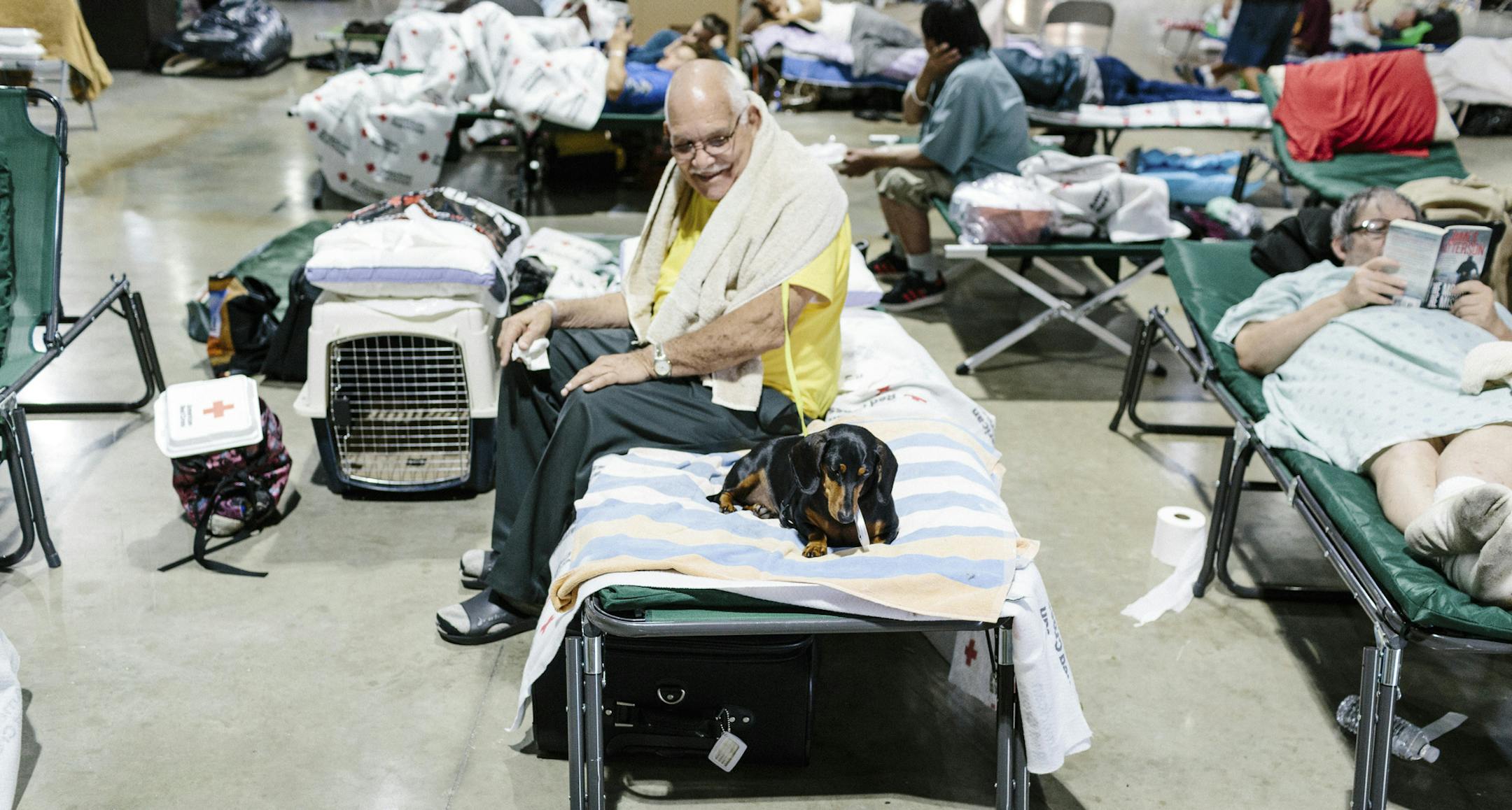 Peter Parkes sits on a cot with his dog, Obama, at an American Red Cross hurricane shelter at the Miami-Dade Fairgrounds in Miami, Sept. 13, 2017. With Irma now a post-tropical cyclone moving north, officials in Florida, Georgia and South Carolina sought to prepare residents for a long recovery. (Jason Henry/The New York Times)