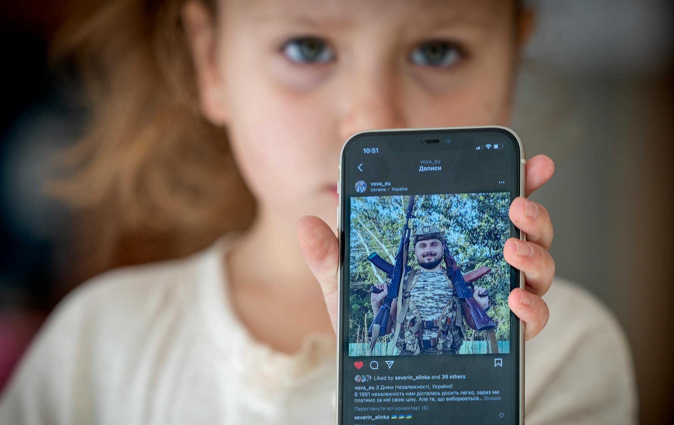 Ukrainian refugee Solomiia Kuchma, 5, shows off a photo of her father Yolodumir, who is currently fighting on the front lines in Ukraine, from her host home. Solomiia's mother Natalia Kuchma's and her aunt Yaroslava Kalutska fled the country in September to live in Minneapolis.