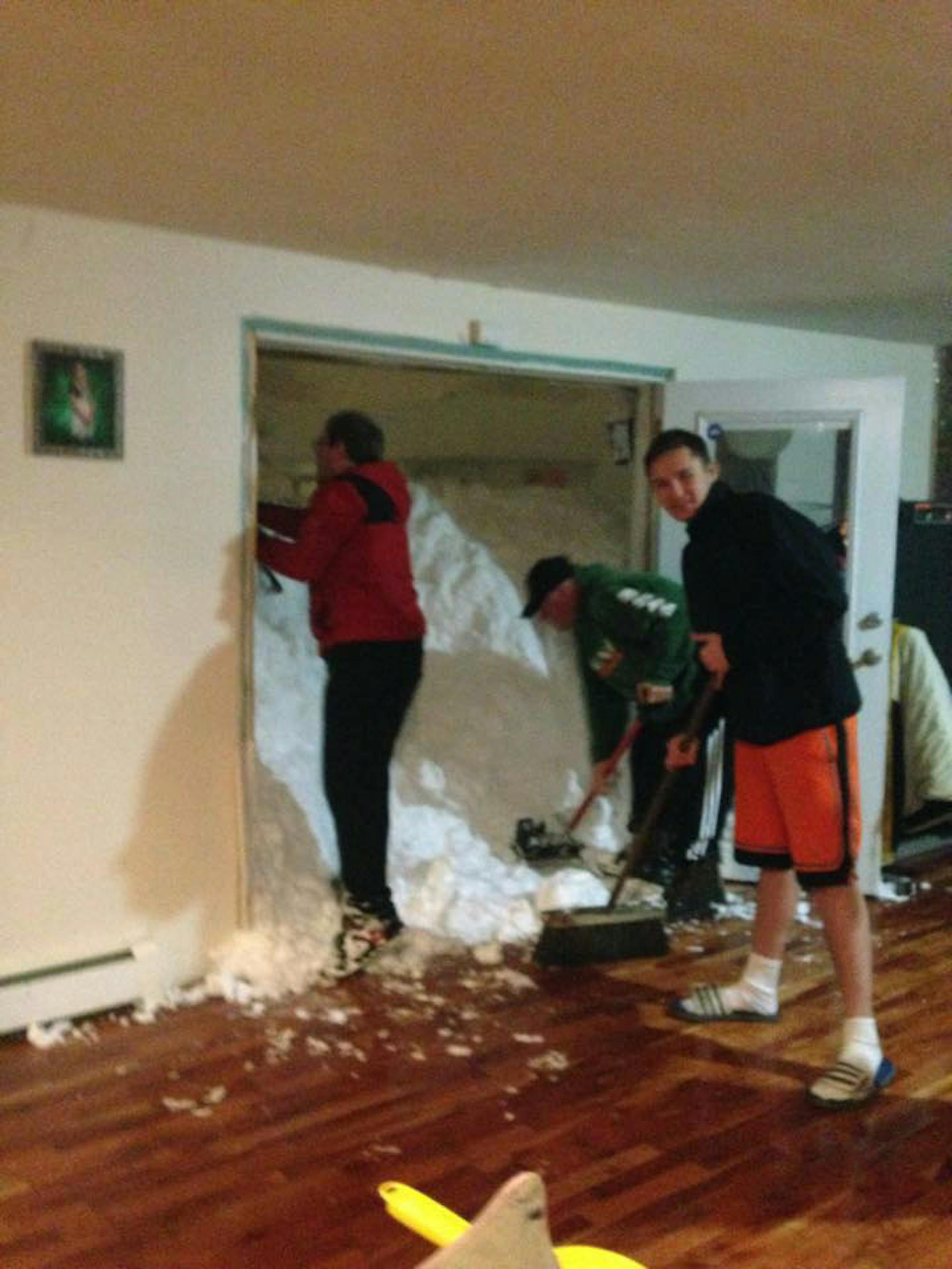 In this photo provided by Chrissy Hazard, Mark Hazard, his son Jason and Bryan Juda shovel out the snow from the home of Chrissy Hazard on Tuesday, Nov. 18, 2014 in Cheektowaga, N.Y. A ferocious lake-effect storm that trapped people on highways and in homes under up to 6 feet of snow continued to bear down on the Buffalo area Wednesday even as another looming storm was expected to dump another 2 to 3 feet on the region. (AP Photo/Courtesy of Chrissy Hazard )