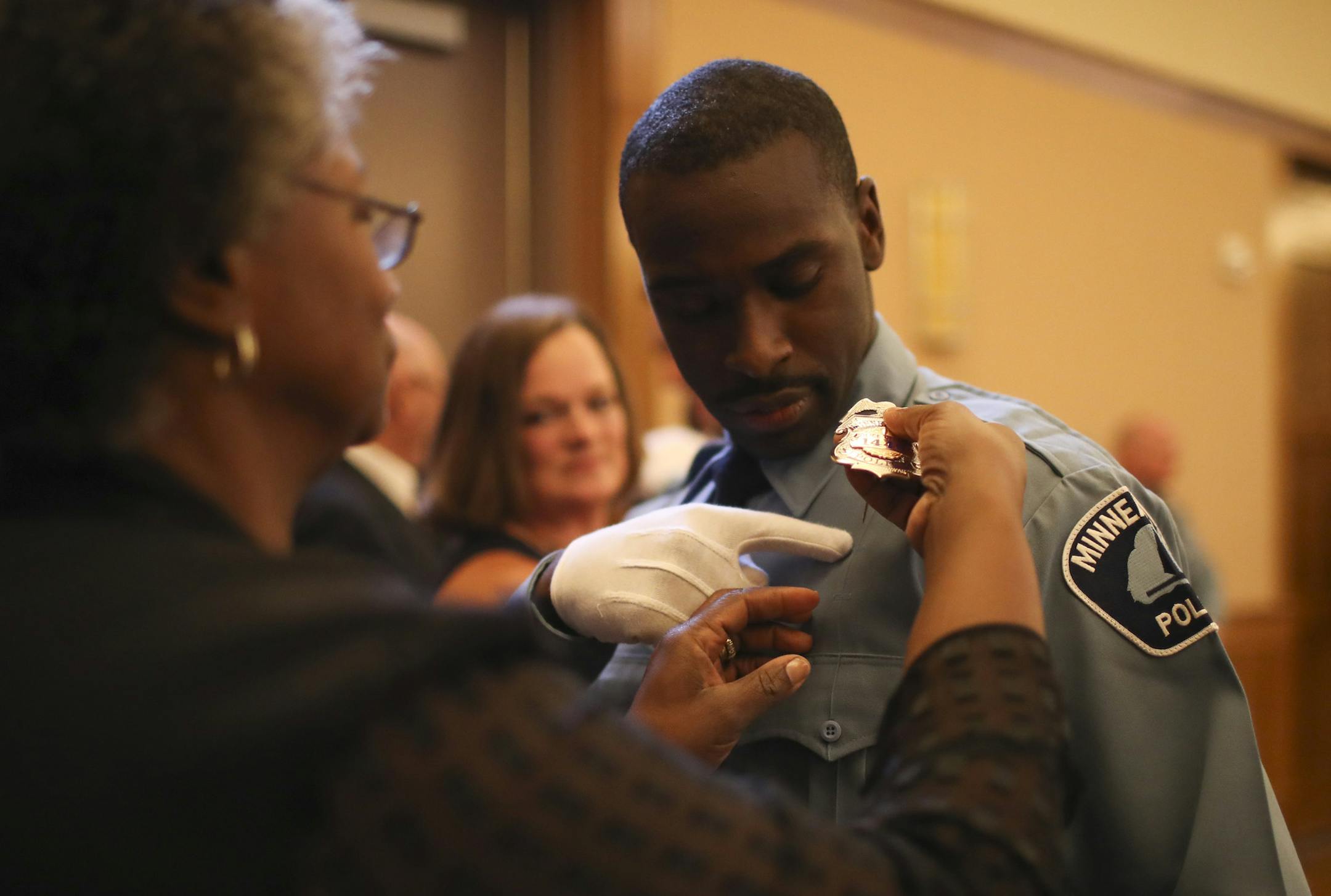 Timothy Davis, Jr. showed his mother, Clarissa Davis, where to pin his Minneapolis Police Department badge before he took the oath of office with the other members of the class Wednesday evening. ] JEFF WHEELER ï jeff.wheeler@startribune.com Eight new members of the Minneapolis Police Department were sworn in Wednesday evening, June 1, 2016 in a ceremony at St. Mary's Greek Orthodox Church. In addition, two Park Police officers were sworn in, too. All were already city employees before atte