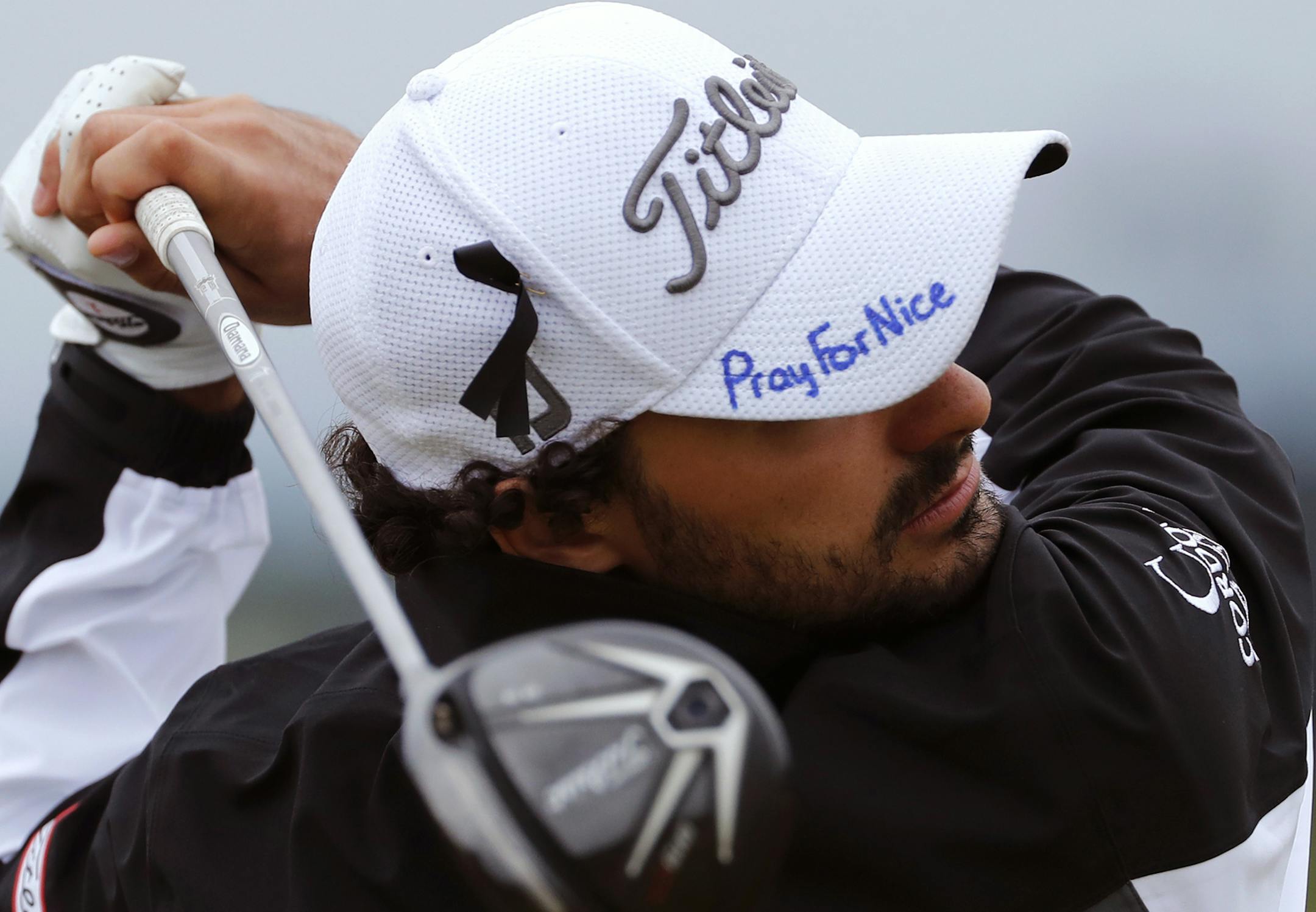 Clement Sordet of France plays his shot from the 7th tee, wearing a cap that has the words 'Pray for Nice' written by hand on it, during the second round of the British Open Golf Championship at the Royal Troon Golf Club in Troon, Scotland, Friday, July 15, 2016. France was ravaged by its third attack in two years when a large white truck mowed through revelers gathered for Bastille Day fireworks in Nice, late Thursday, as it bore down on the crowd for more than a mile along the Riviera city's f
