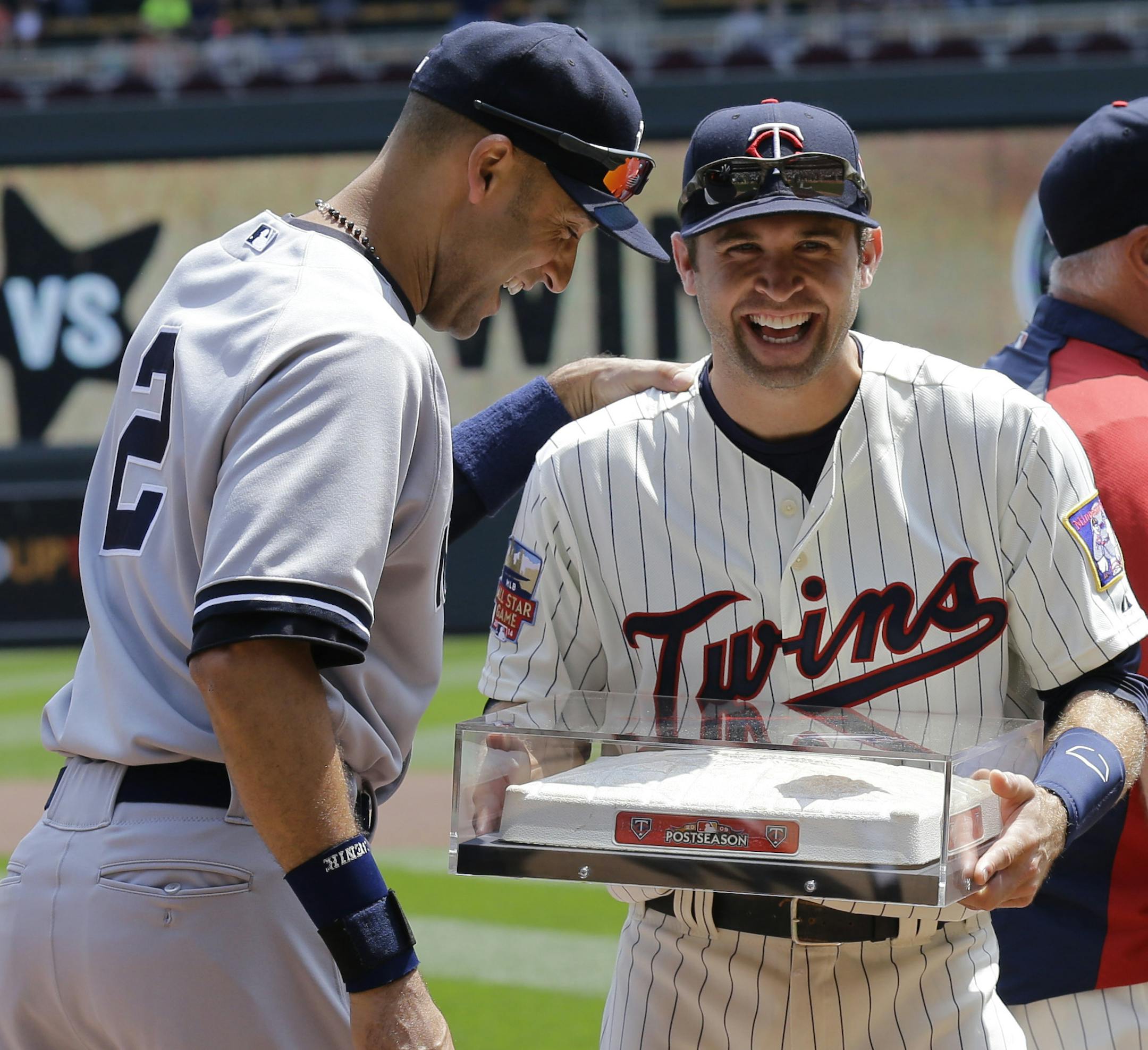 New York Yankees shortstop Derek Jeter, left, and Minnesota Twins second baseman Brian Dozier, right, share a laugh as Dozier presents Jeter with the last second base used in the Metrodome as the Twins honor Jeter before a baseball game in Minneapolis, Saturday, July 5, 2014. (AP Photo/Ann Heisenfelt)