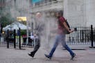 FILE - In this June 16, 2021 file photo, people walk through steam from a street grating during the morning commute in New York. Companies around the 