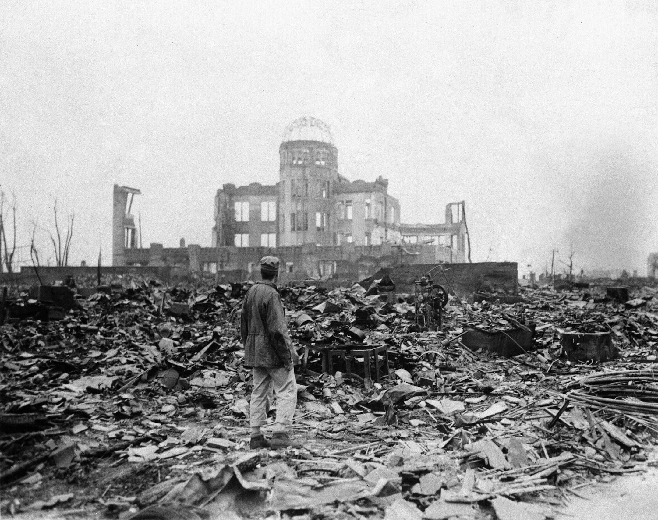 FILE - In this Sept. 8, 1945, file photo, an allied correspondent stands in a sea of rubble before the shell of a building that once was a movie theater in Hiroshima, western Japan, a month after the first atomic bomb ever used in warfare was dropped by the U.S. to hasten Japan's surrender. Many people exposed to radiation developed symptoms such as vomiting and hair loss. Most of those with severe radiation symptoms died within three to six weeks. Others who lived beyond that developed health p