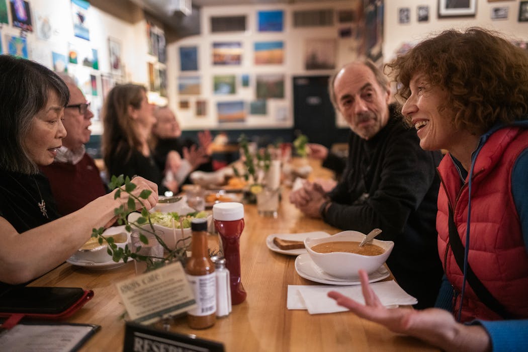 Anna Bonavita, right, gathers a group at a communal table at Gigi’s Cafe in  Minneapolis on Jan. 18. 