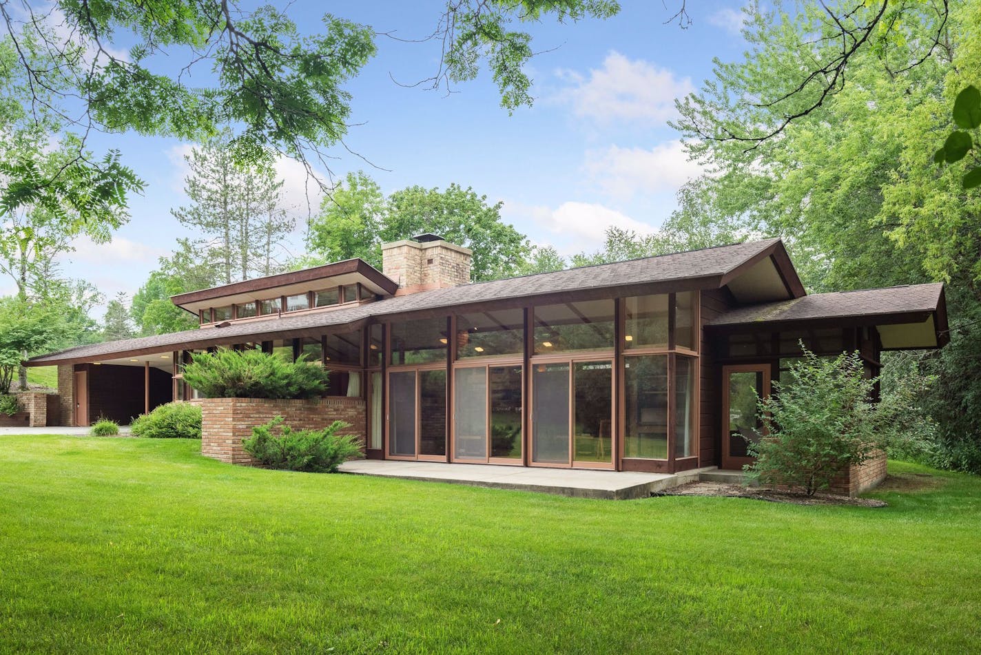 A low-slung one-story house designed by Frank Lloyd Wright associated John Howe is nestled into a hillside in Rochester.