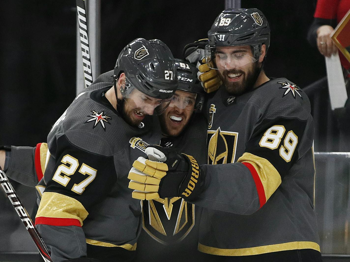 Vegas Golden Knights defenseman Shea Theodore (27), center Jonathan Marchessault, center, and right wing Alex Tuch (89) celebrate Tuch's goal against the San Jose Sharks during the second period of Game 5 of an NHL hockey second-round playoff series, Friday, May 4, 2018, in Las Vegas. (AP Photo/John Locher)