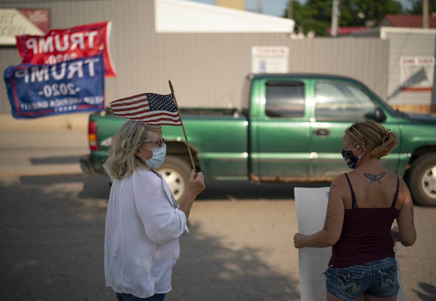 Linda Nelson, left, and Nicole Meyer visited while demonstrating with about 45 other social justice supporters Thursday afternoon as a pro-Trump pickup drove past in Appleton, Minn.