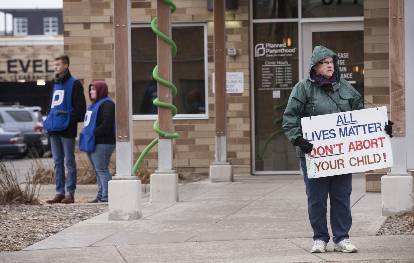 Lynn Sandquist, right, of Mounds View holds, an anti-abortion sign outside of Planned Parenthood's local headquarters. Jon Hanson and Molly Wesslund, from left, wait to greet and escort patients into the clinic.