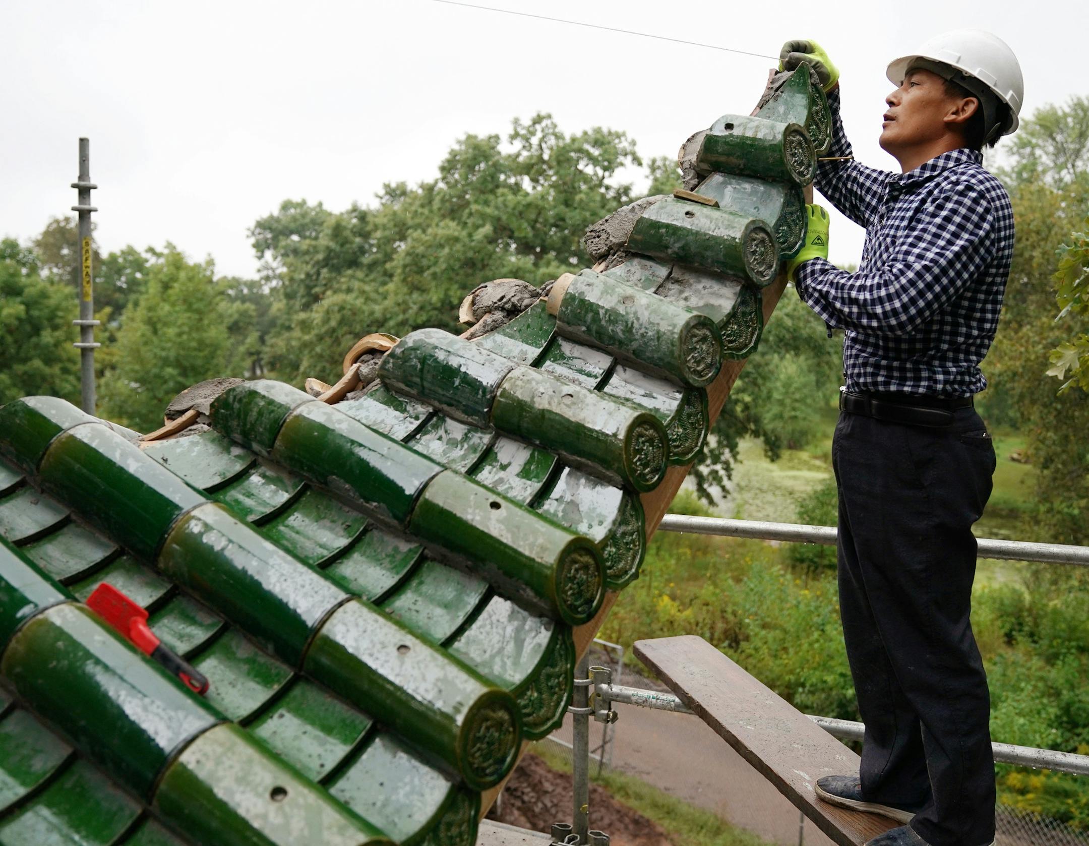 Lou Han Ming worked from scaffolding on the second story of the Chinese pavilion. ] ANTHONY SOUFFLE • anthony.souffle@startribune.com Workers continued on construction of a Chinese pavilion, along with a Chinese friendship garden, along the shore of Lake Phalen Tuesday, Aug. 28, 2018 in St. Paul, Minn. The pavilion, a replica of the Aiwan Pavilion in Changsha, China, a St. Paul sister city, was built in China, then deconstructed and shipped to the U.S. for assembly here.