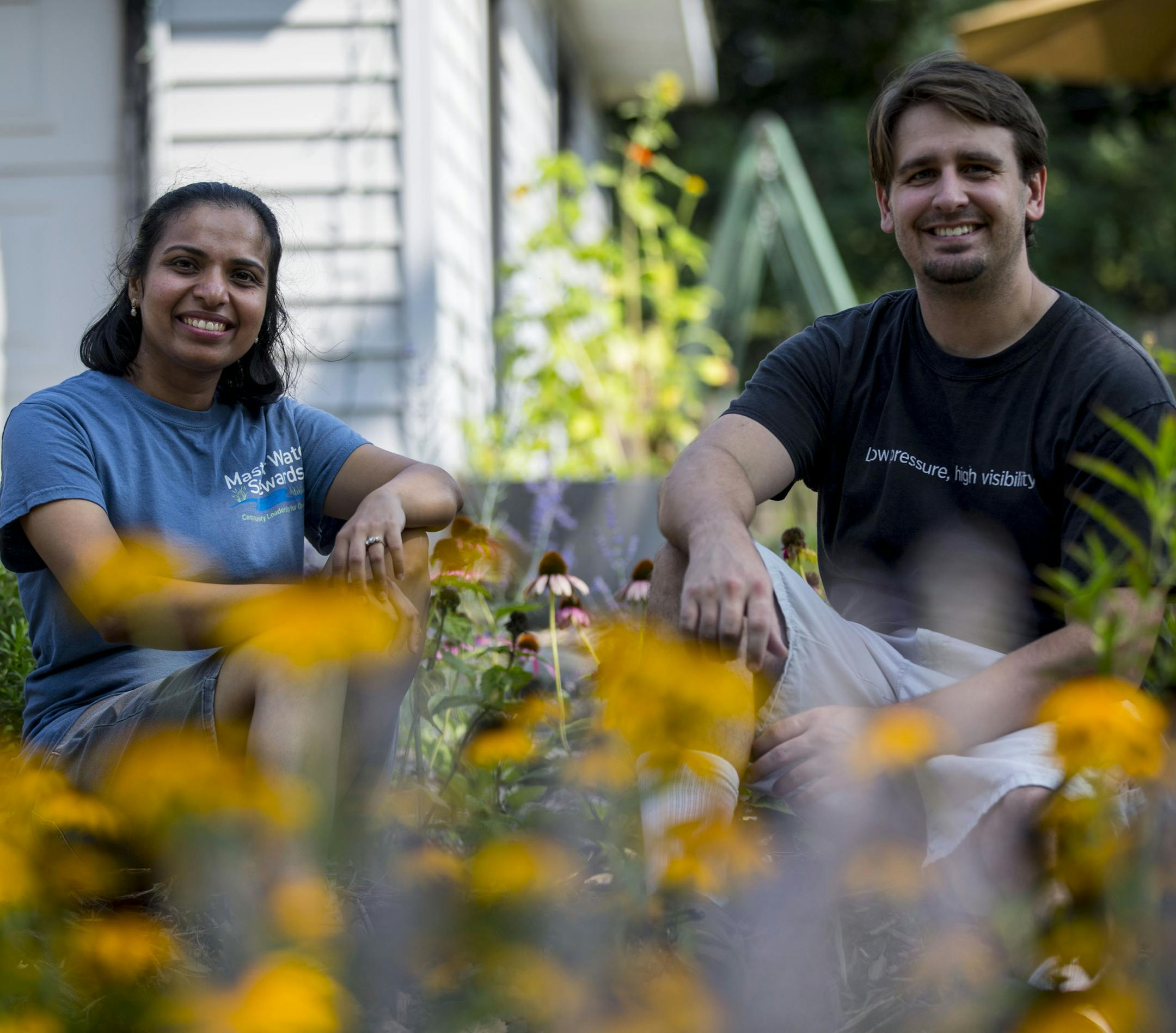 Harsha Amin-Thom and her husband, Alex Thom, pose for a photo in their rain garden. Alex helped Harsha dig out the slope and build the retaining wall. ] ALEX KORMANN • alex.kormann@startribune.com Harsha Amin-Thom is a Master Water Steward who created a rain garden in her yard and is helping to instruct her neighbors and community on how to better harness rain water to be re-purposed to grow beautiful gardens. It is environmentally responsible and cost efficient using a rain drain and a g