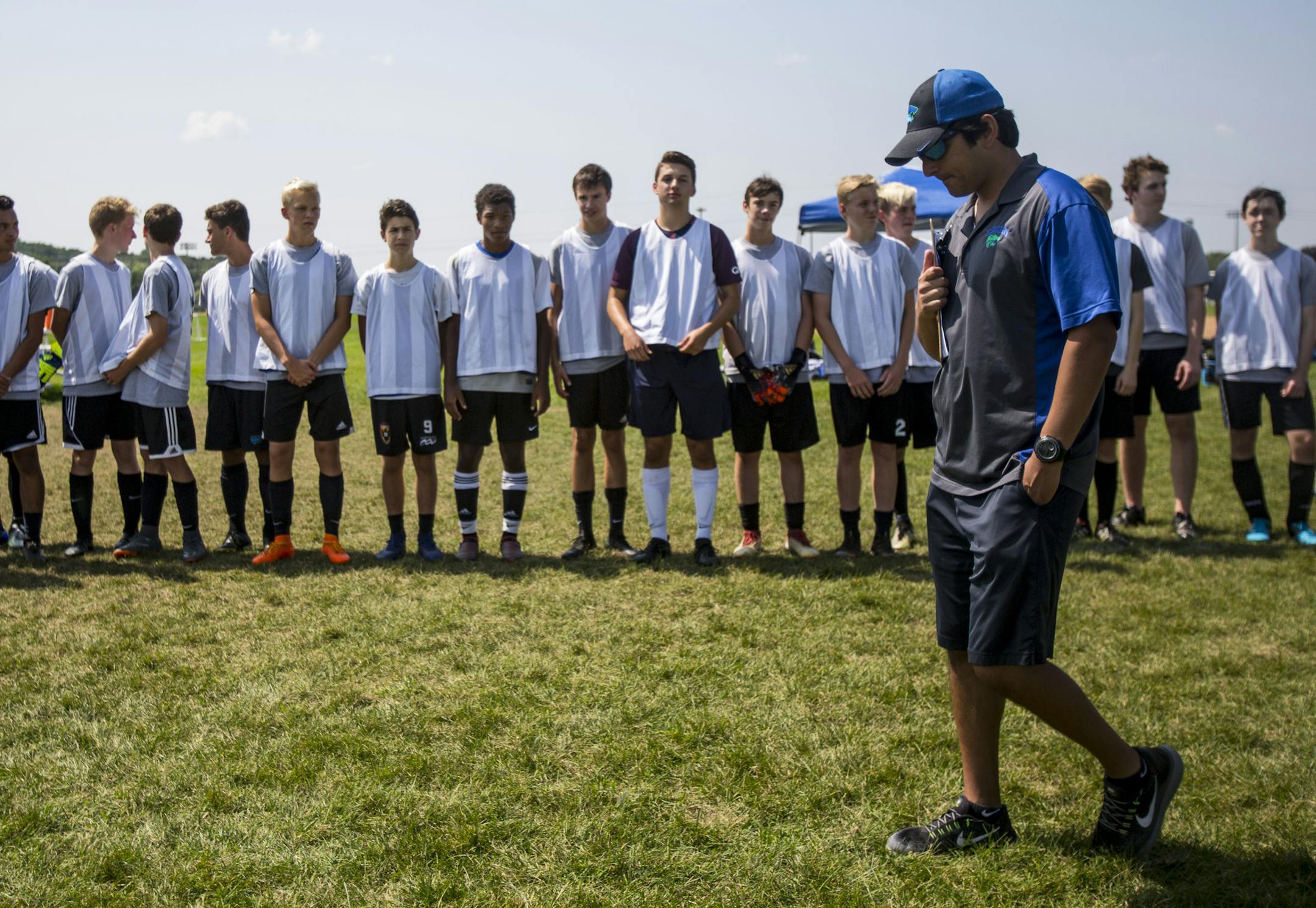 Coach Ozturk walks down the line of prospective boys soccer players at the start of practice. ] ALEX KORMANN • alex.kormann@startribune.com The Eagan High Schools boys and girls soccer teams began practicing on Monday August 13, 2018 in 90 degree heat at the school. Coach Bulut Ozturk, known to his players as simply "Turk", is taking on the unique role as the head coach of both the boys and girls varsity programs this season. Dozens of students came to try out for the teams but the coach