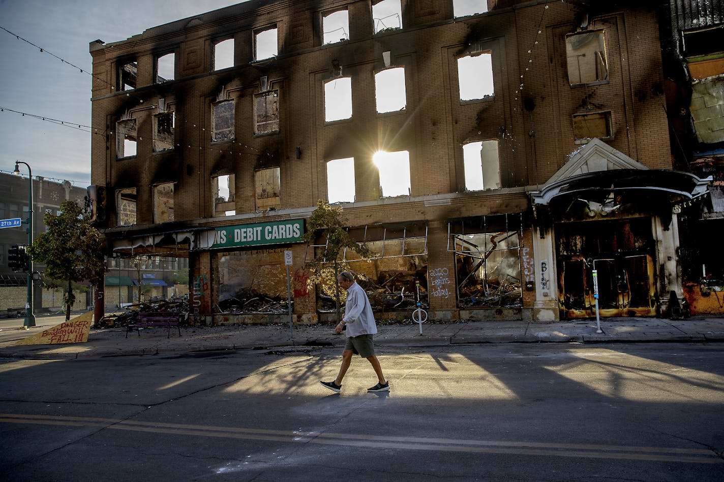 A man walks past a damaged building on May 31, following overnight protests over the death of George Floyd in Minneapolis.