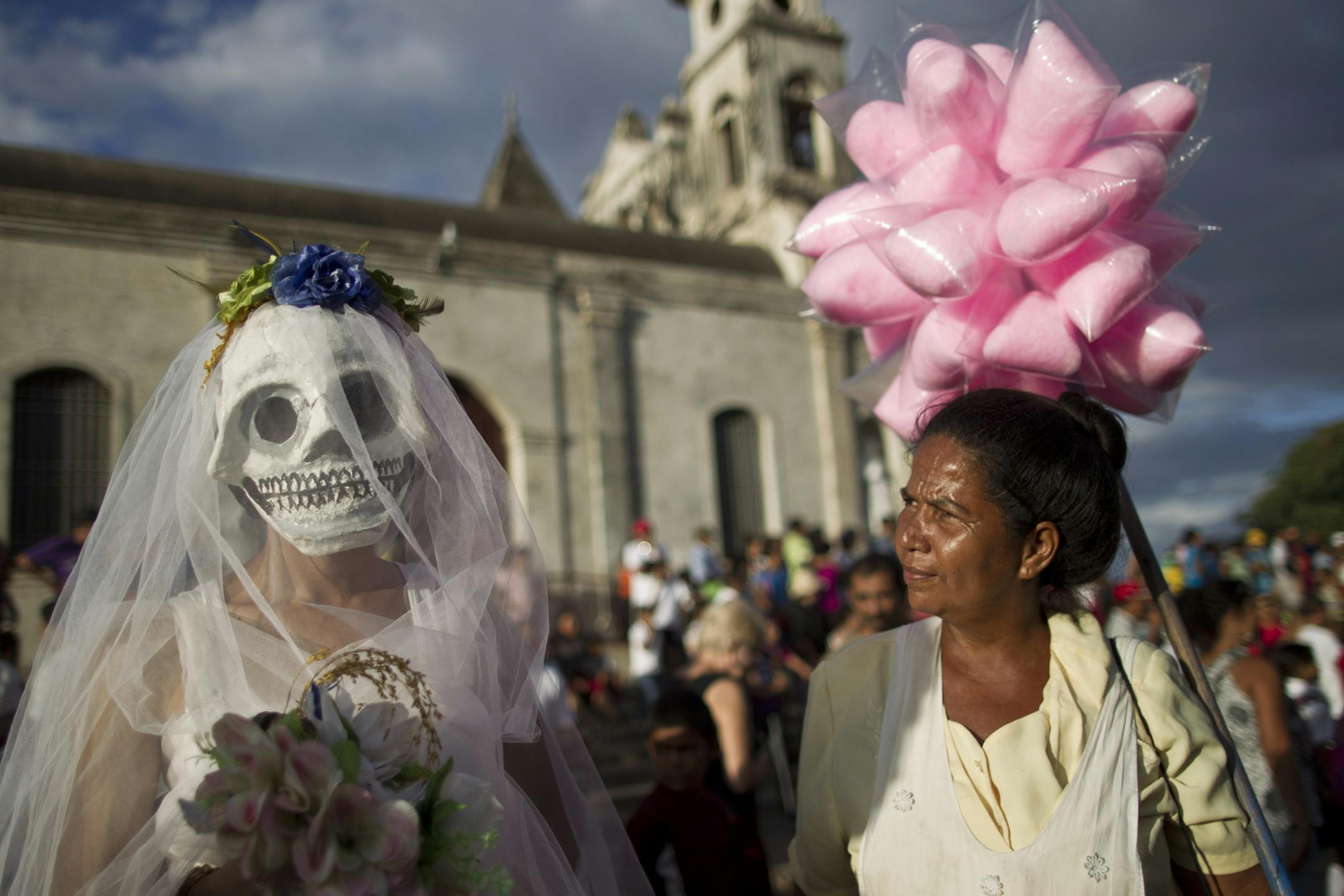 A street vendor, right, looks at a disguised reveler during celebrations marking the 9th International Poetry Festival honoring Nicaraguan poet, priest and former Nicaragua's Culture Minister, Ernesto Cardenal, not in picture, in Granada, Nicaragua, Wednesday, Feb 20, 2013. The festival is attended by more than 300 poets from some 60 countries. (AP Photo/Esteban Felix)