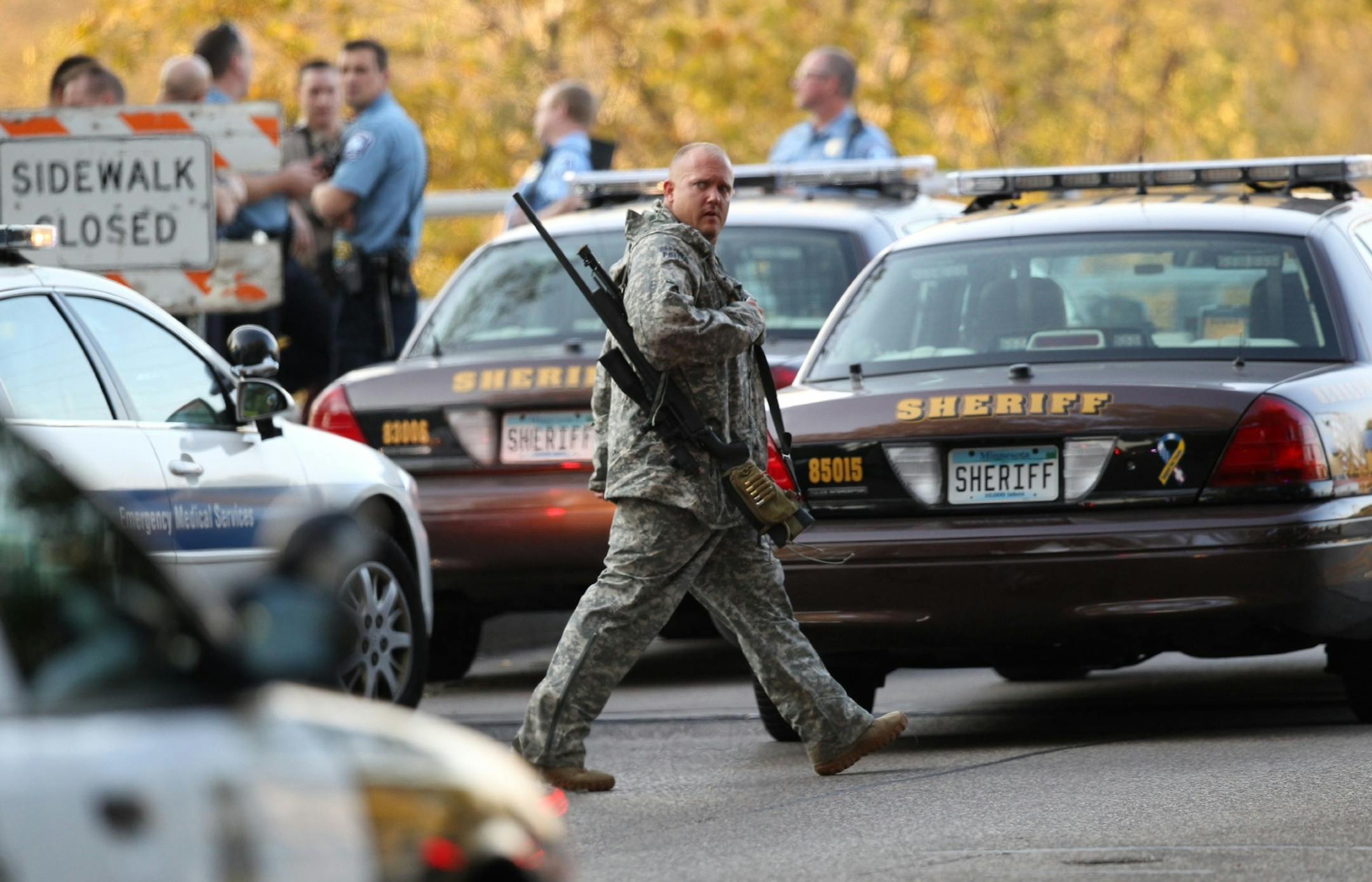 FILE - In this Sept. 27, 2012 file photo, an officer walks through the area as police investigate a shooting at Accent Signage Systems in Minneapolis. The family of Jacob Beneke, one of six people killed in the shooting, announced Friday, Feb. 1, 2013, they are suing the company and the attacker's estate claiming Accent Signage should have known that the attacker, Andrew Engeldinger, had violent tendencies, was mentally unstable and was a potential danger to others. (AP Photo/Star Tribune, Renee