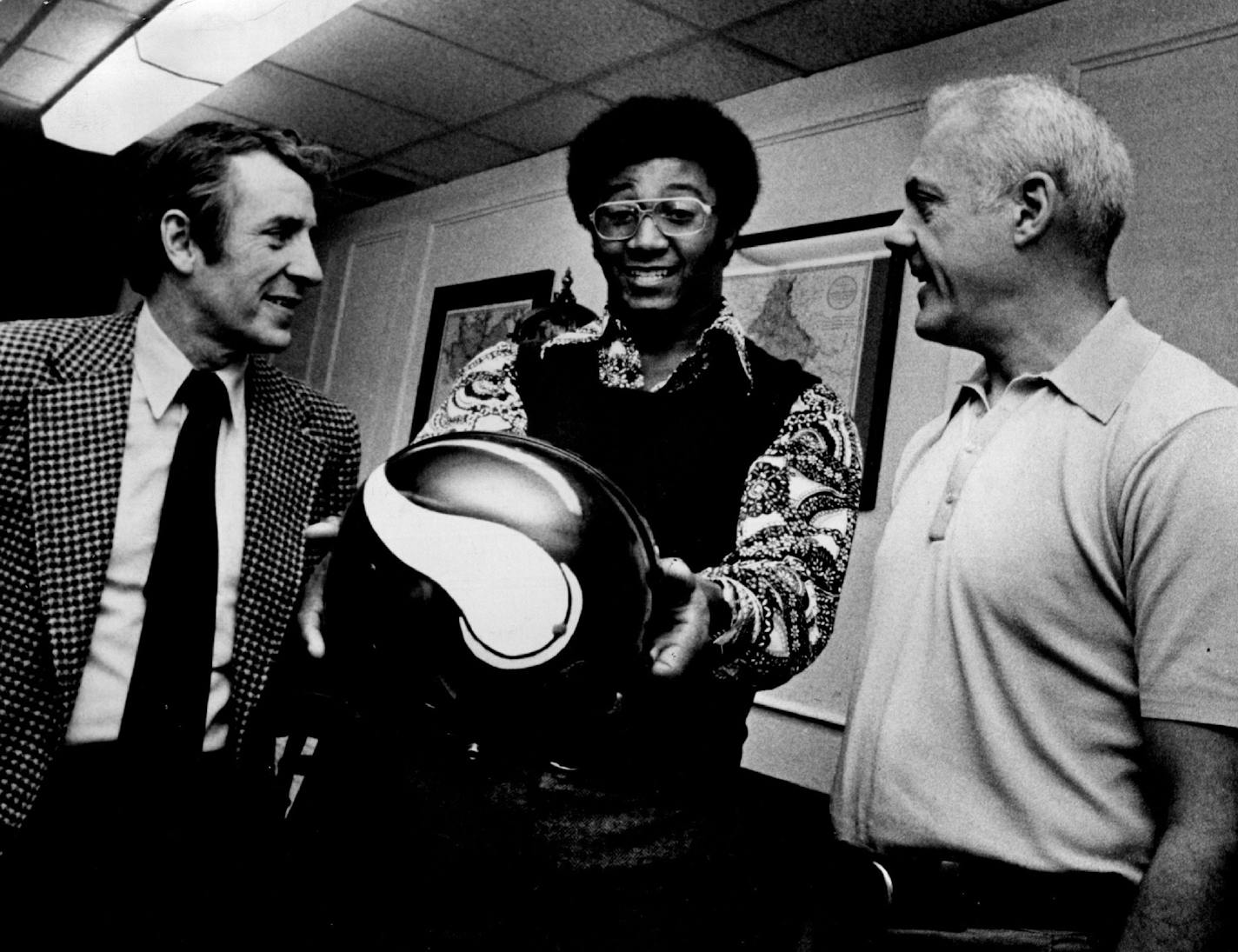 Chuck Foreman, the Viking's first-round draft choice form University of Miami, looked at the helmet he'll be wearing as a running back for Minnesota on February 28, 1973. General manager Jim Finks, left, and coach Bud Grant, right, talked contract details with Foreman.